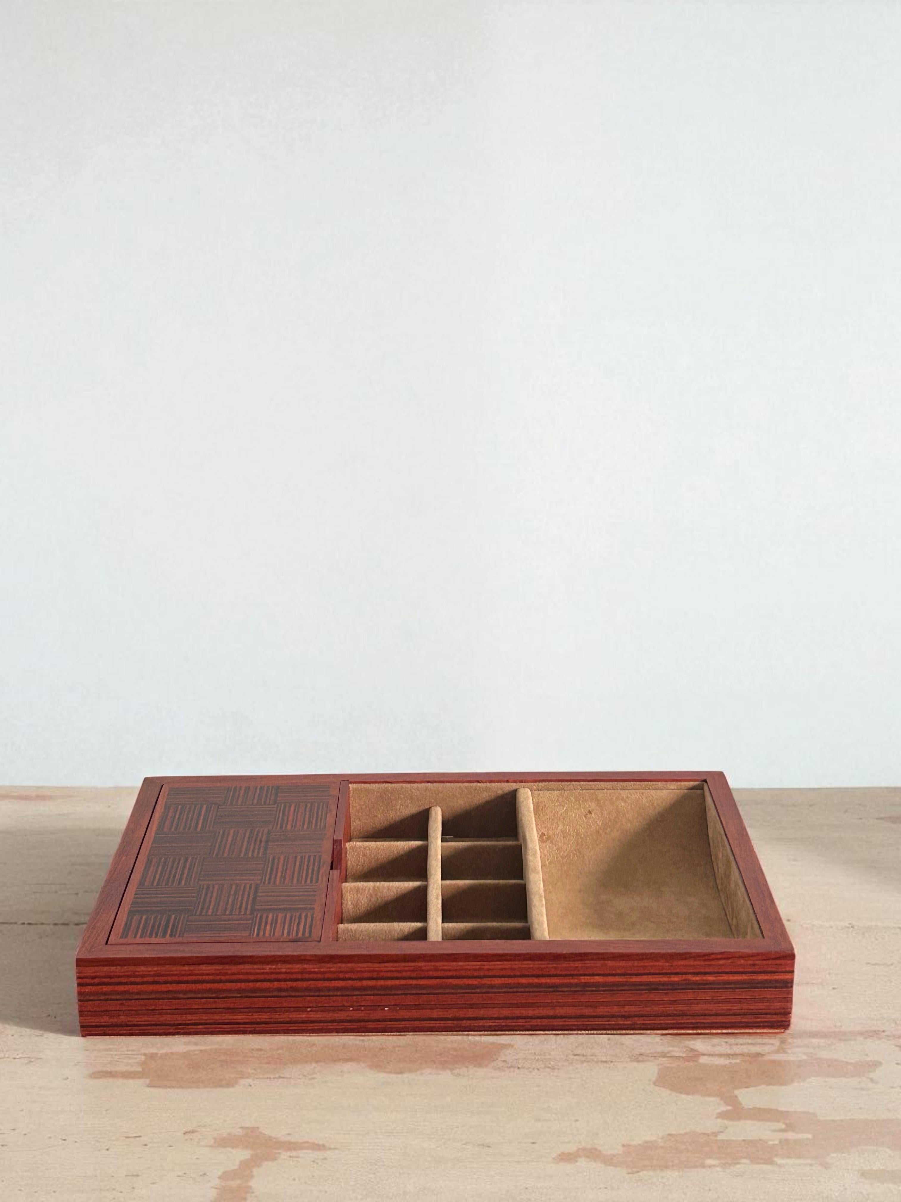 Un organisateur de valet de chambre magnifiquement conçu avec un extérieur en bois riche et chaud, un couvercle à incrustation géométrique et un intérieur doux et doublé de daim. Conçue pour les besoins quotidiens, cette pièce permet de ranger les