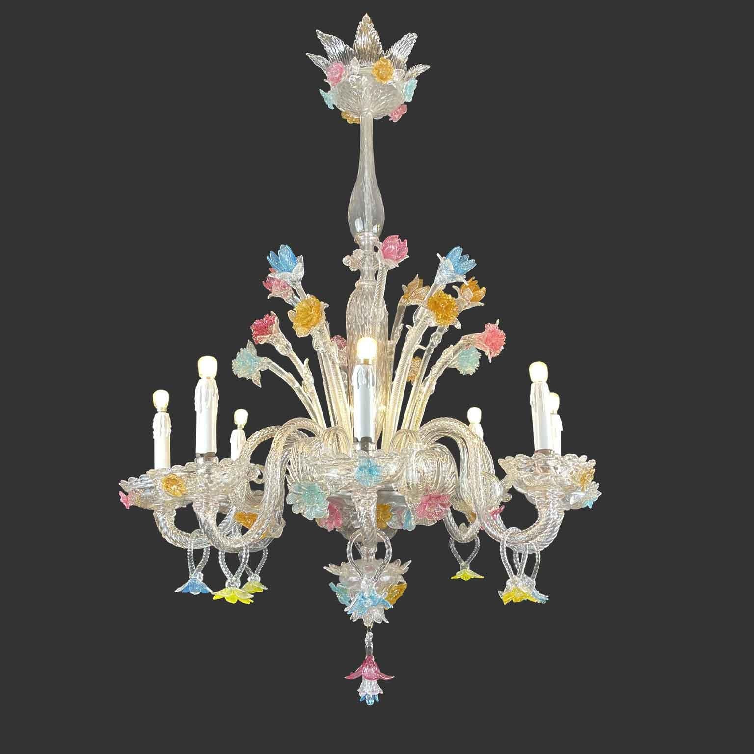 A timeless Venetian blown clear chandelier with pink, blue and yellow details, a Murano circular chandelier, elegant structure finely decorated with eight curved arms ending with upwards corolla shaped bobeiges. Rose, yellow and blue floral elements