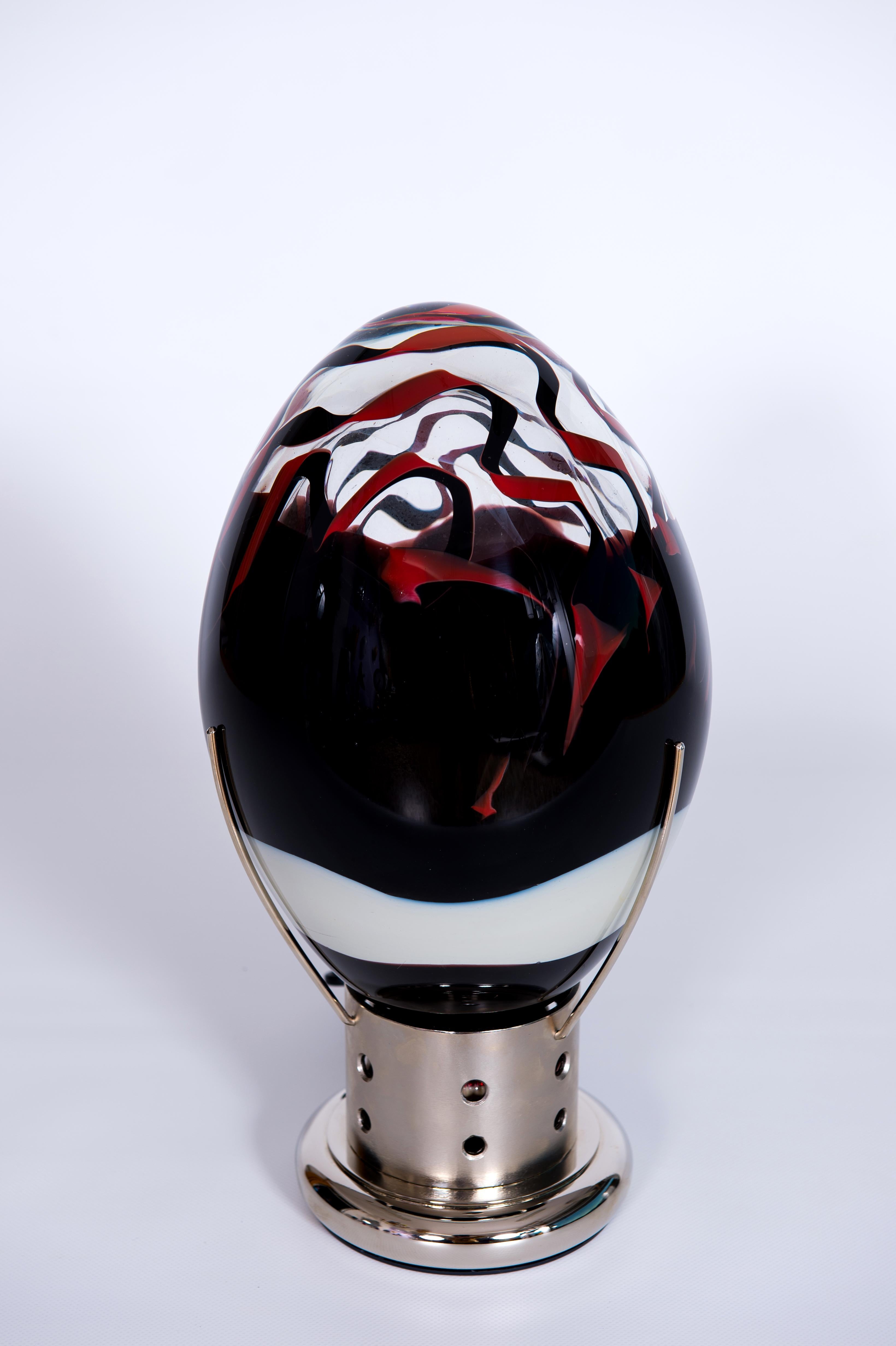 Elegante lampe œuf vénitienne Murano Glass Vibrant Red Dark Metal Base 1990 Italy.
Remarquable lampe de table en forme d'œuf vénitien, dotée d'une coquille en verre de Murano d'un rouge éclatant et d'une base en métal poli.
Une lampe de table œuf
