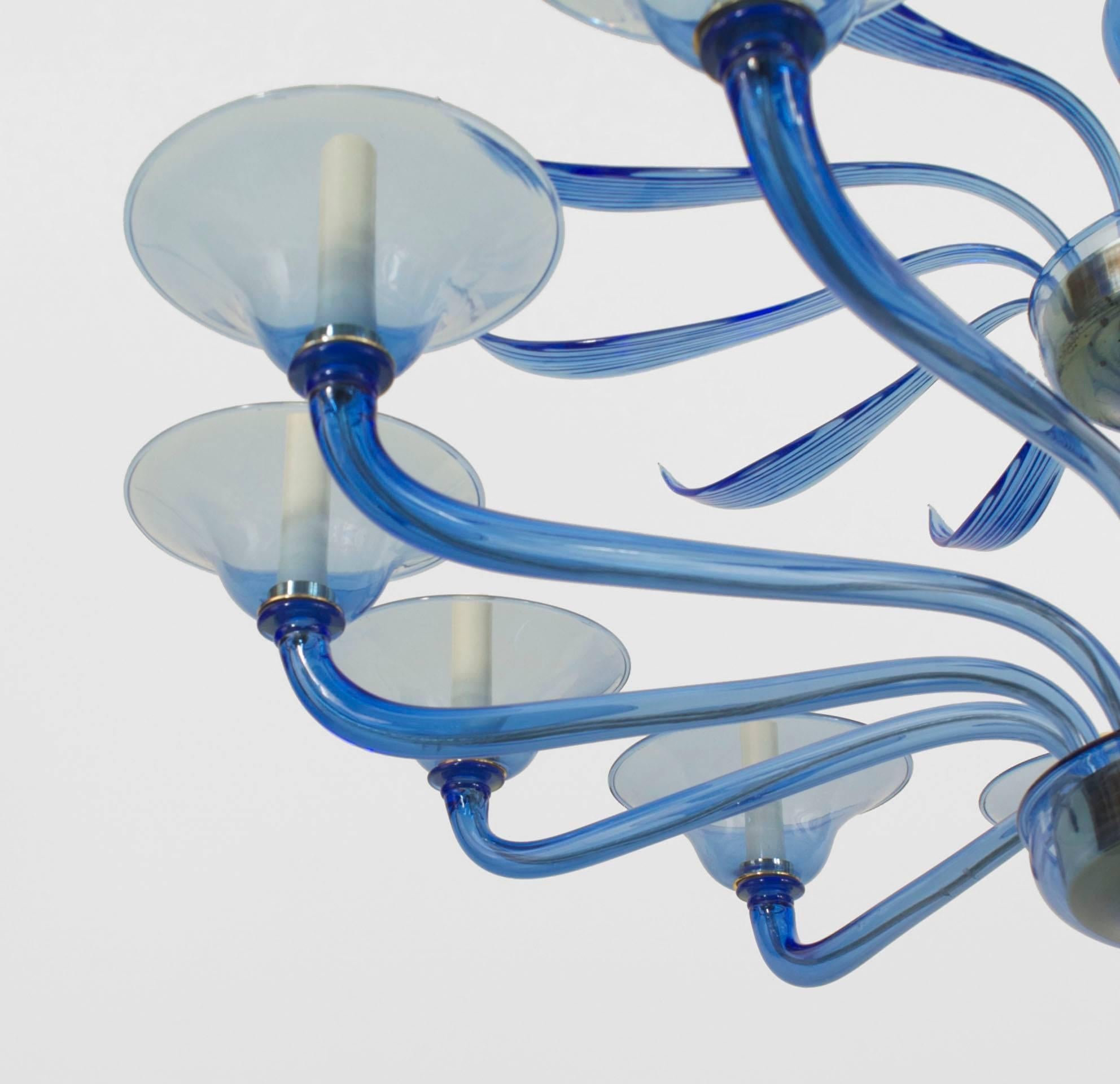 Italian Venetian Murano 1940s style (modern) blue glass chandelier with 12 scroll arms under a tier of 12 fluted feathers emanating from a centre shaft with a final bottom (Murano maker decal).

       