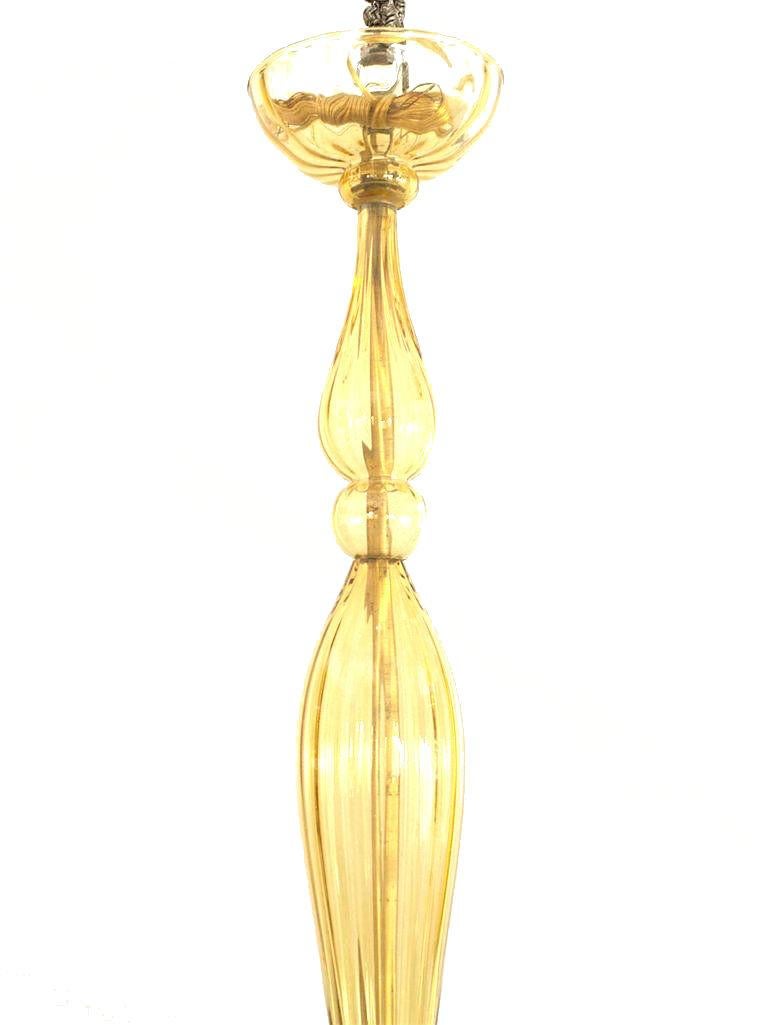 Italian Venetian-Style Murano (1940s) oval shaped amber glass chandelier with 12 arms emanating from a tall center shaft holding fluted round disc bobesches & a tiered finial bottom.
