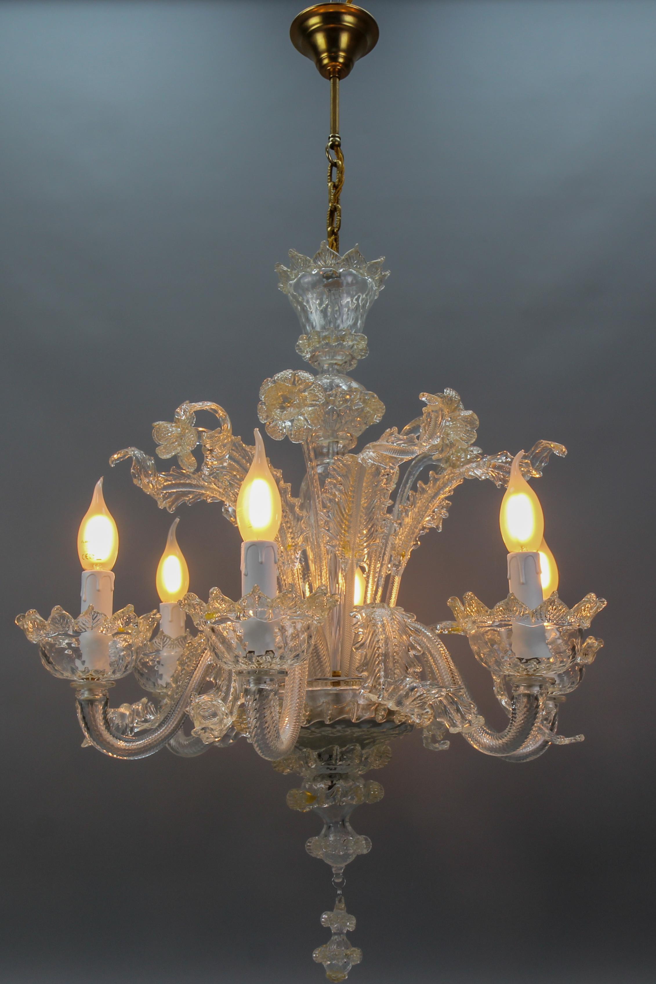 Italian Venetian Murano clear glass and gold dust floral six-light chandelier from the circa 1950s.
This majestic Murano glass chandelier with gold inclusions inside the clear glass features six curved glass arms with candle-style lights and is
