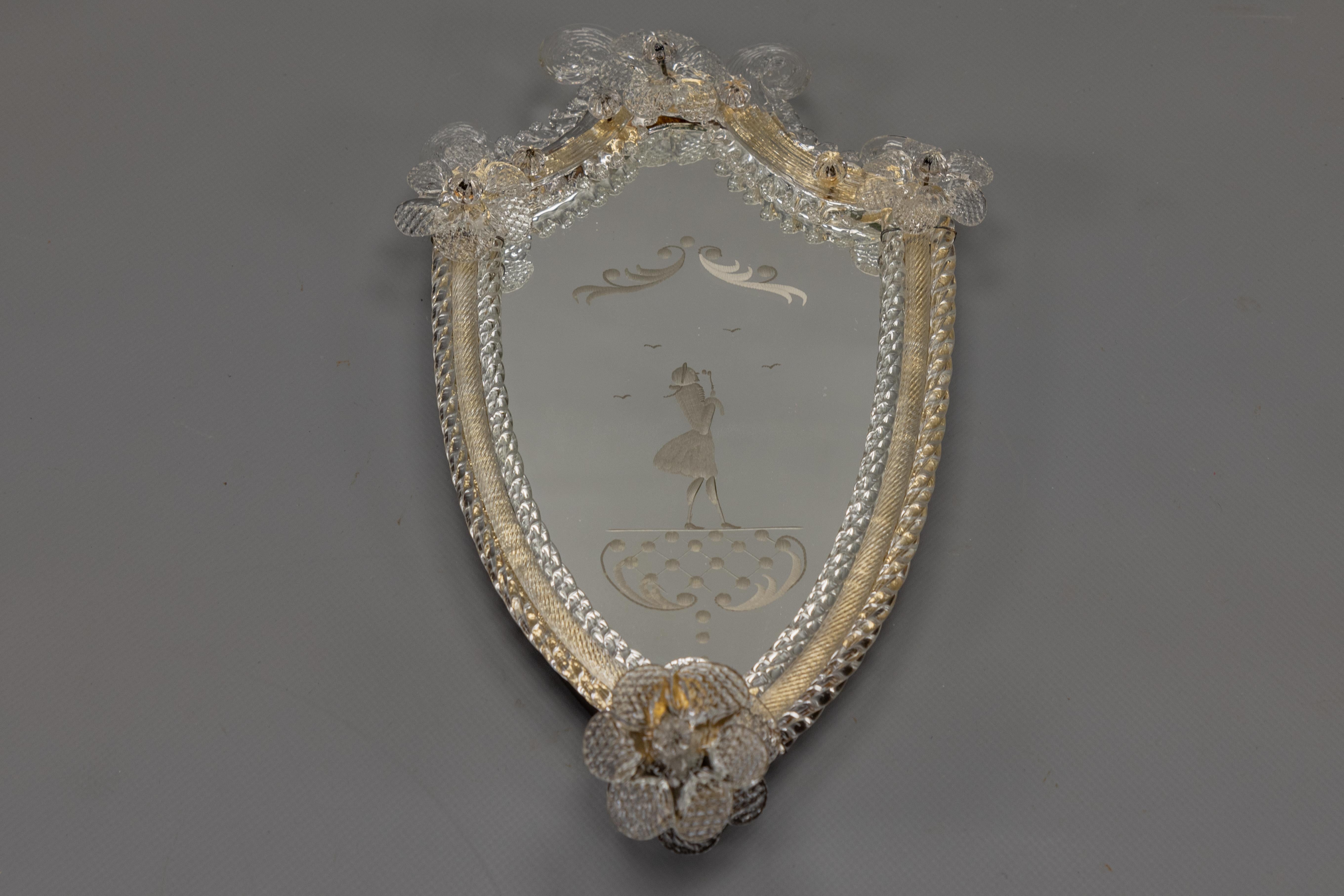 Elegante espejo de pared de Murano en forma de escudo con candelabro y figura grabada, Italia, años 30

Este encantador espejo de pared veneciano, de la década de 1930, presenta un delicado contorno en forma de escudo adornado con detalles de