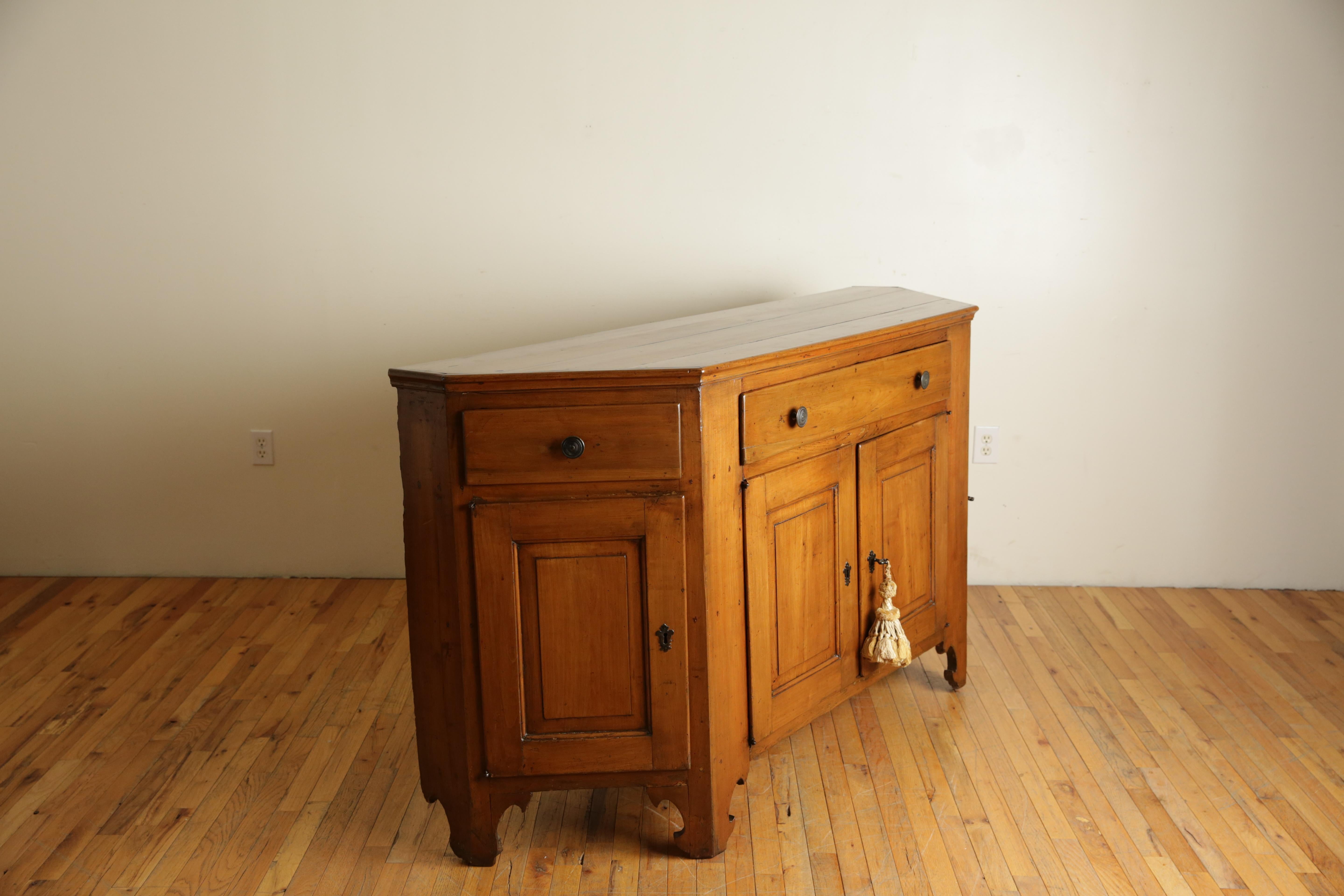 Plateau rectangulaire en forme de scantonata avec un bord convexe mouluré au-dessus d'un boîtier conforme contenant un grand tiroir flanqué de tiroirs plus petits, avec une paire de portes centrales flanquées de portes simples, reposant sur des