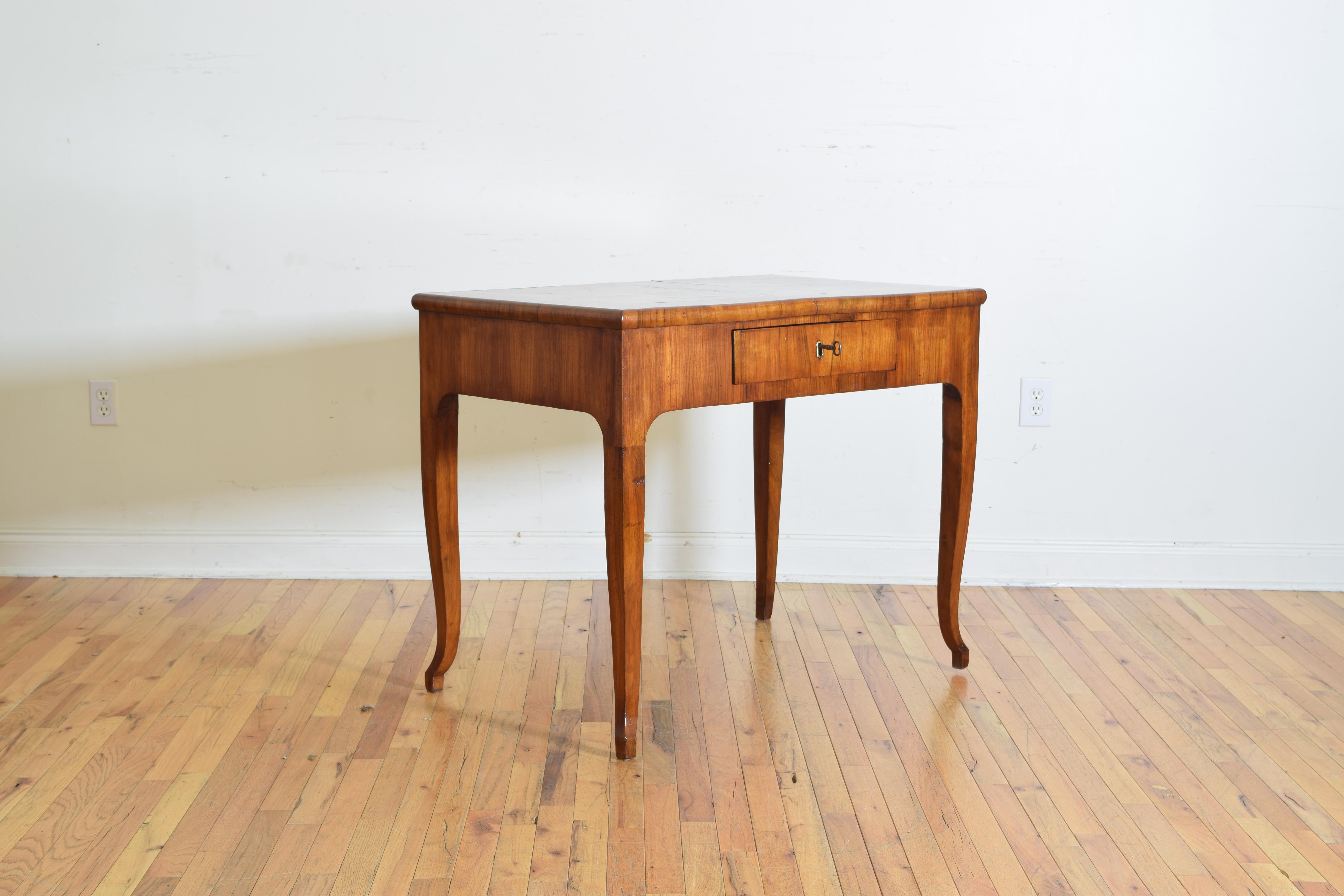 The rectangular top veneered in burl walnut and having one locking drawer, with solid walnut legs curving slightly at the feet.