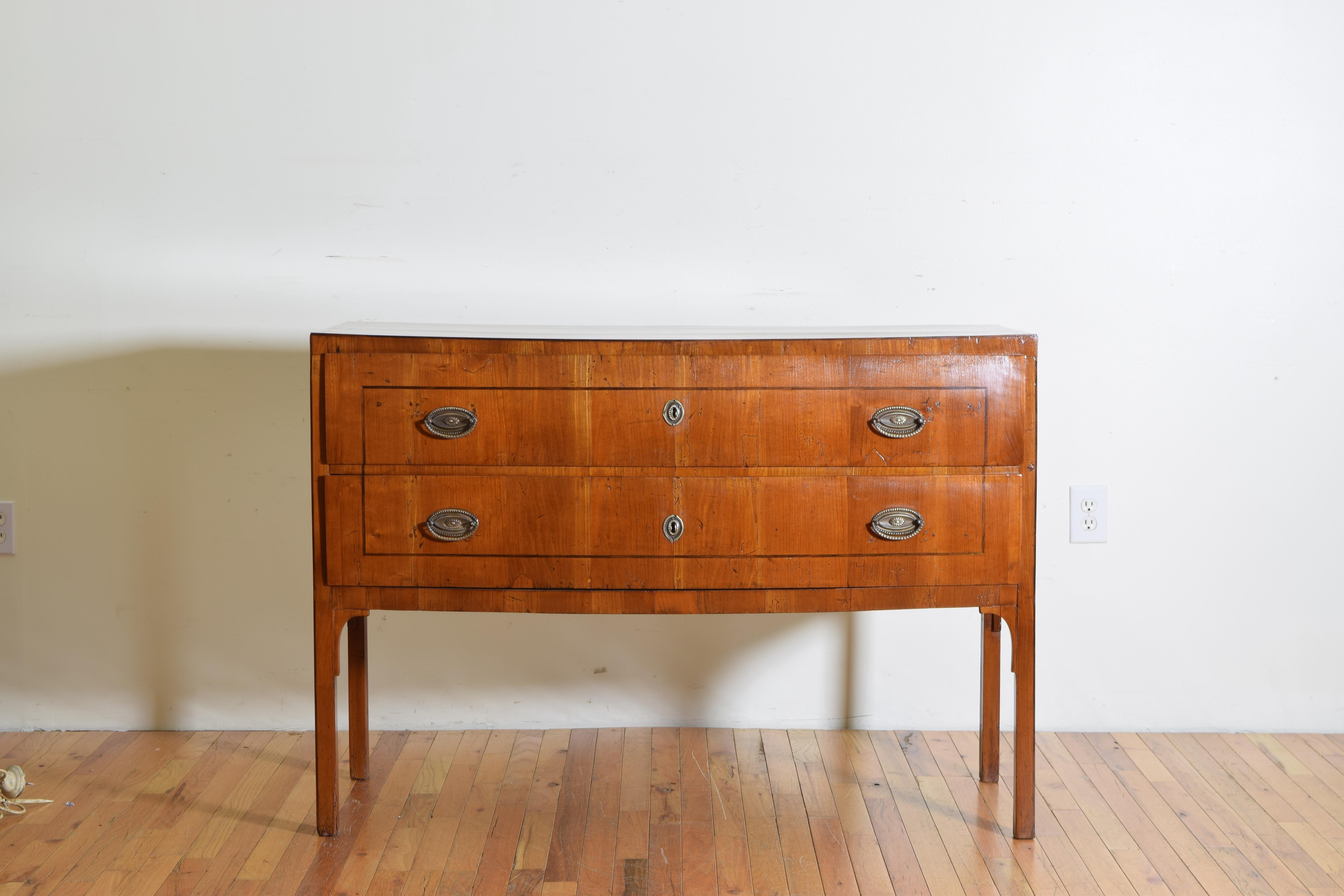 Produced within the first ten years of the early 19th century in the Veneto region of Italy and influenced by the accessibility to the far East that the Adriatic Sea provided, this bowfront 2-drawer cherrywood veneered commode is raised on straight