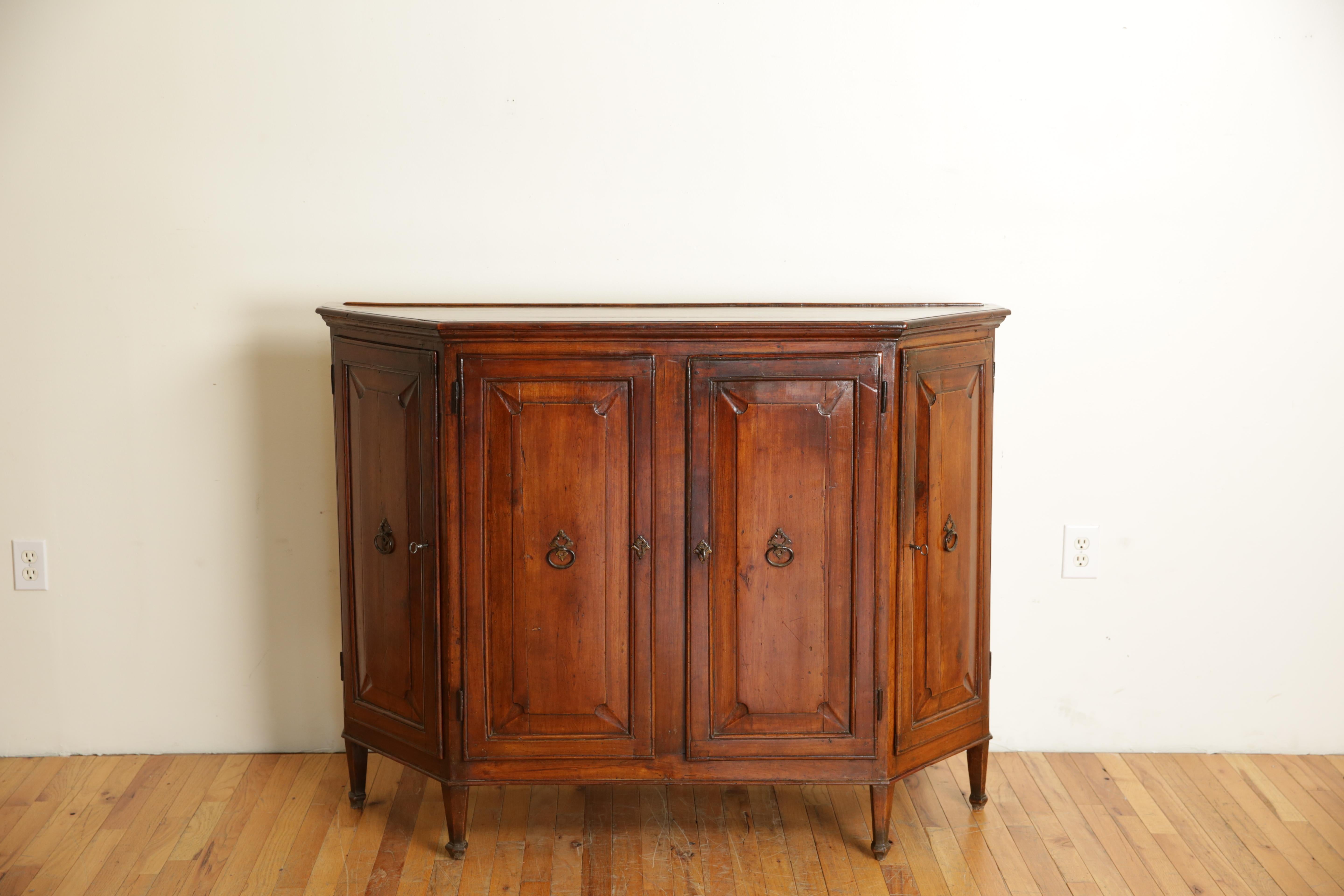 Constructed entirely of solid cherrywood and retraining a beautiful aged patina, having a rectangular top with a raised plate rest molding and with canted corners (scantonata) and molded edges above a conforming case with four paneled and locking