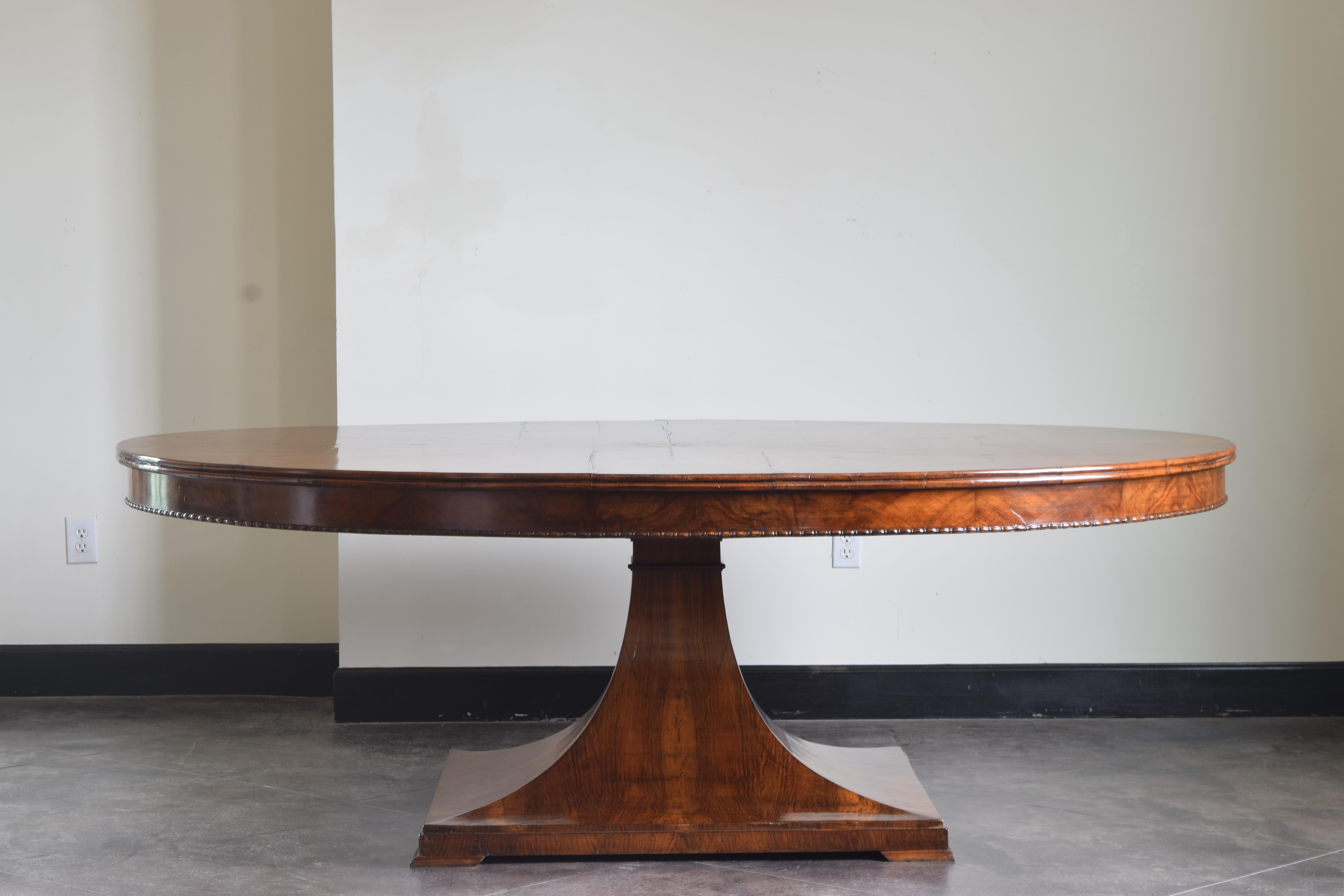 This large and rare center or dining table is veneered in beautifully grained Northern Italian walnut with an startburst center medallion, the molded edge at the top of an apron with a lower egg and dart molded edge, the top rests on a 4 sided
