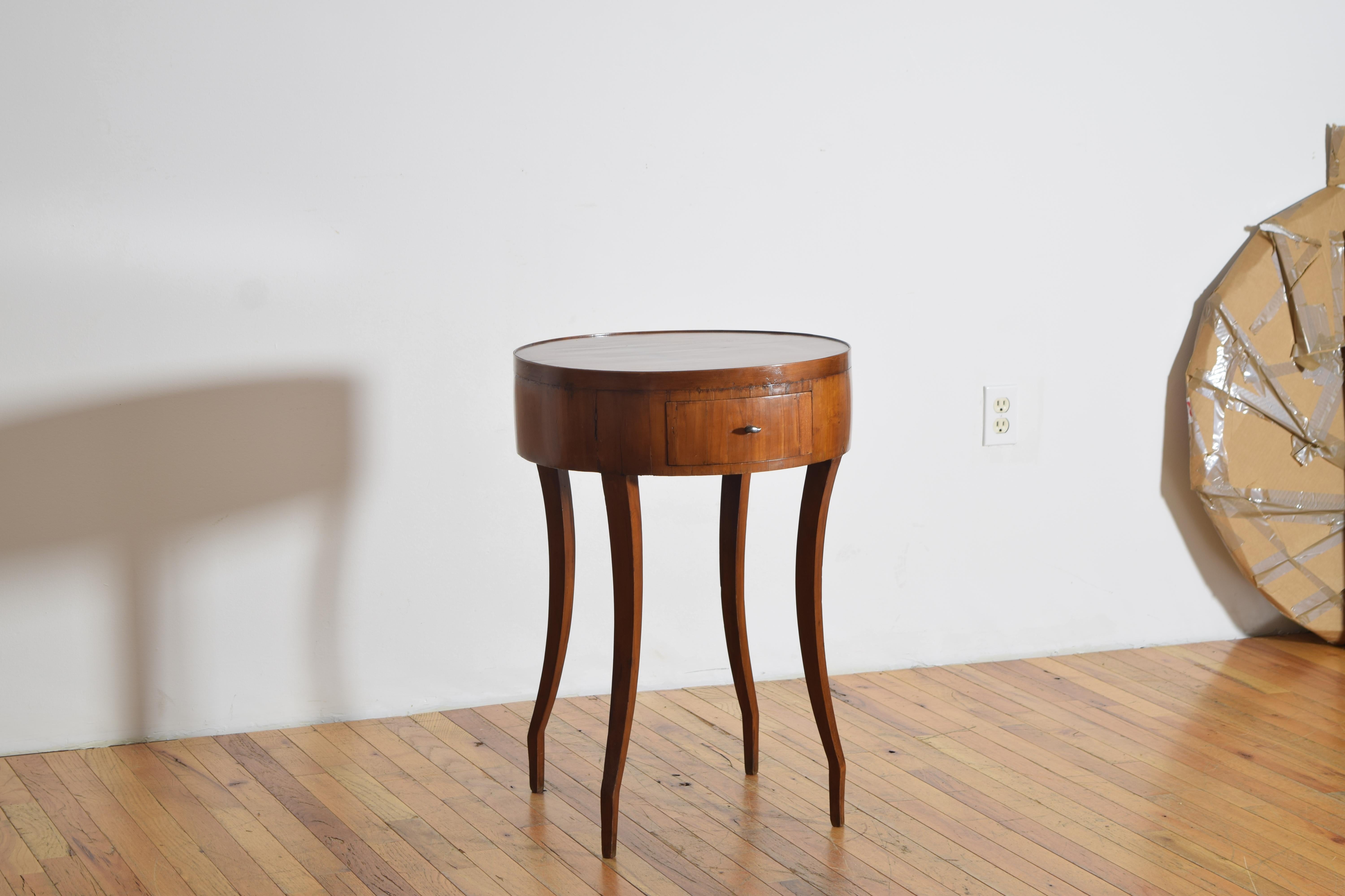 que tiene una tapa circular con un borde de galería ligeramente elevado sobre una caja conforme que aloja un cajón, la caja se eleva sobre patas cónicas cuadradas de forma única