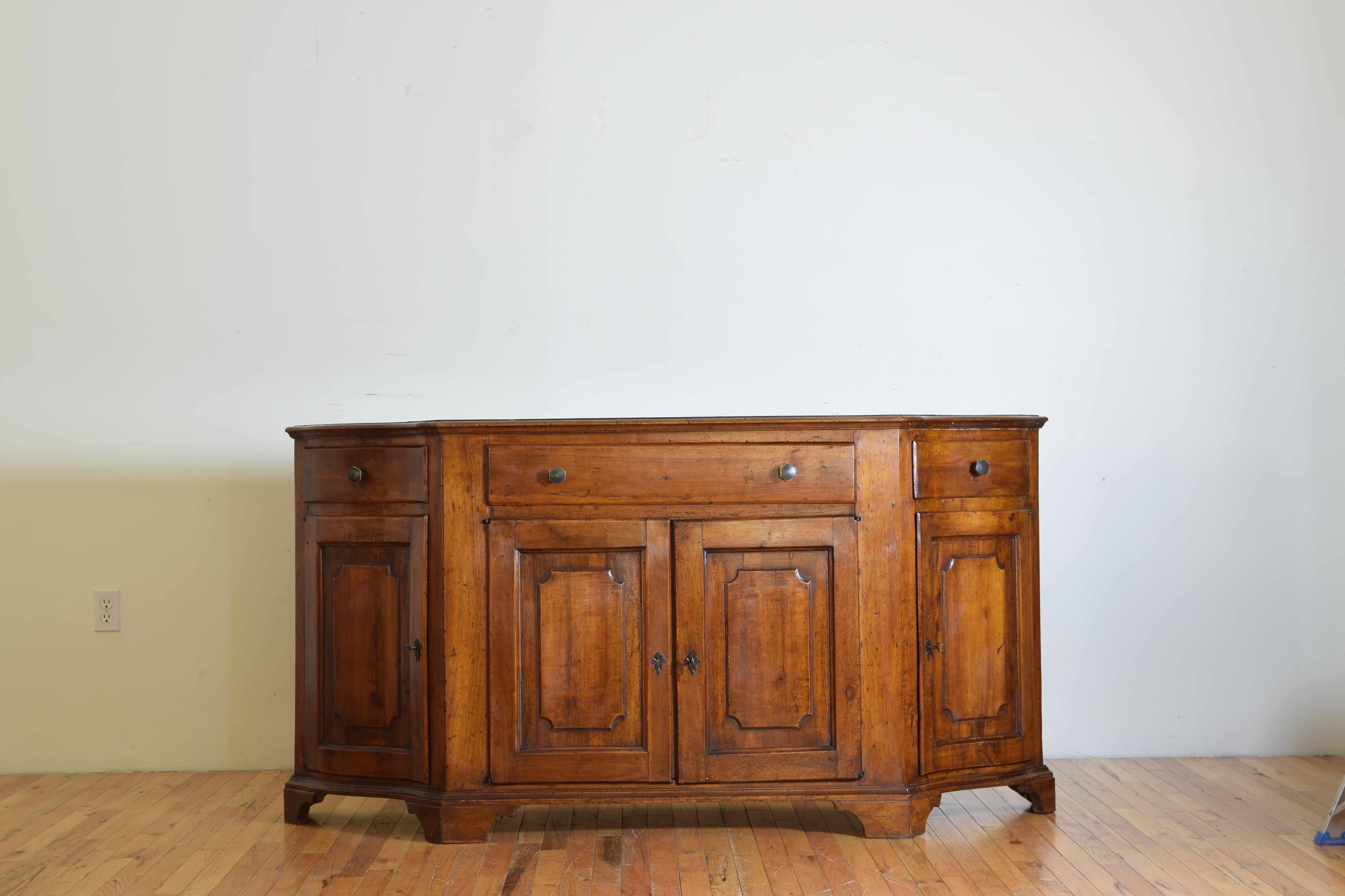 Having a bow-shaped top with molded edge above a conforming case housing three drawers over four paneled doors, the shaped base resting on elongated bracket feet.