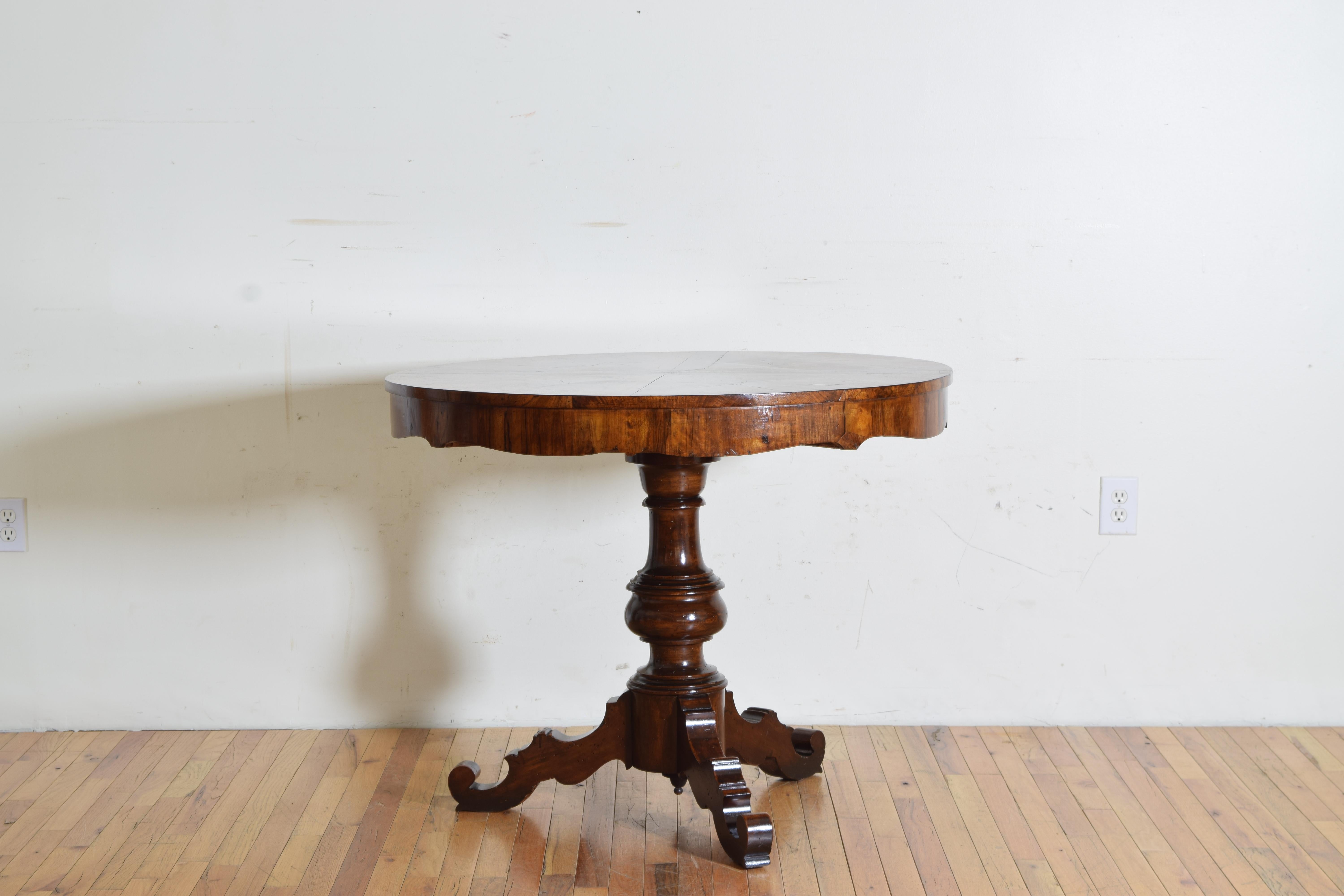 The round top veneered in 12 triangular shaped bookmatched panels joined to form a star-like pattern, the top sits atop a shaped apron also covered in walnut veneer, raised on a boldly turned standard atop a round base issuing three shaped legs with