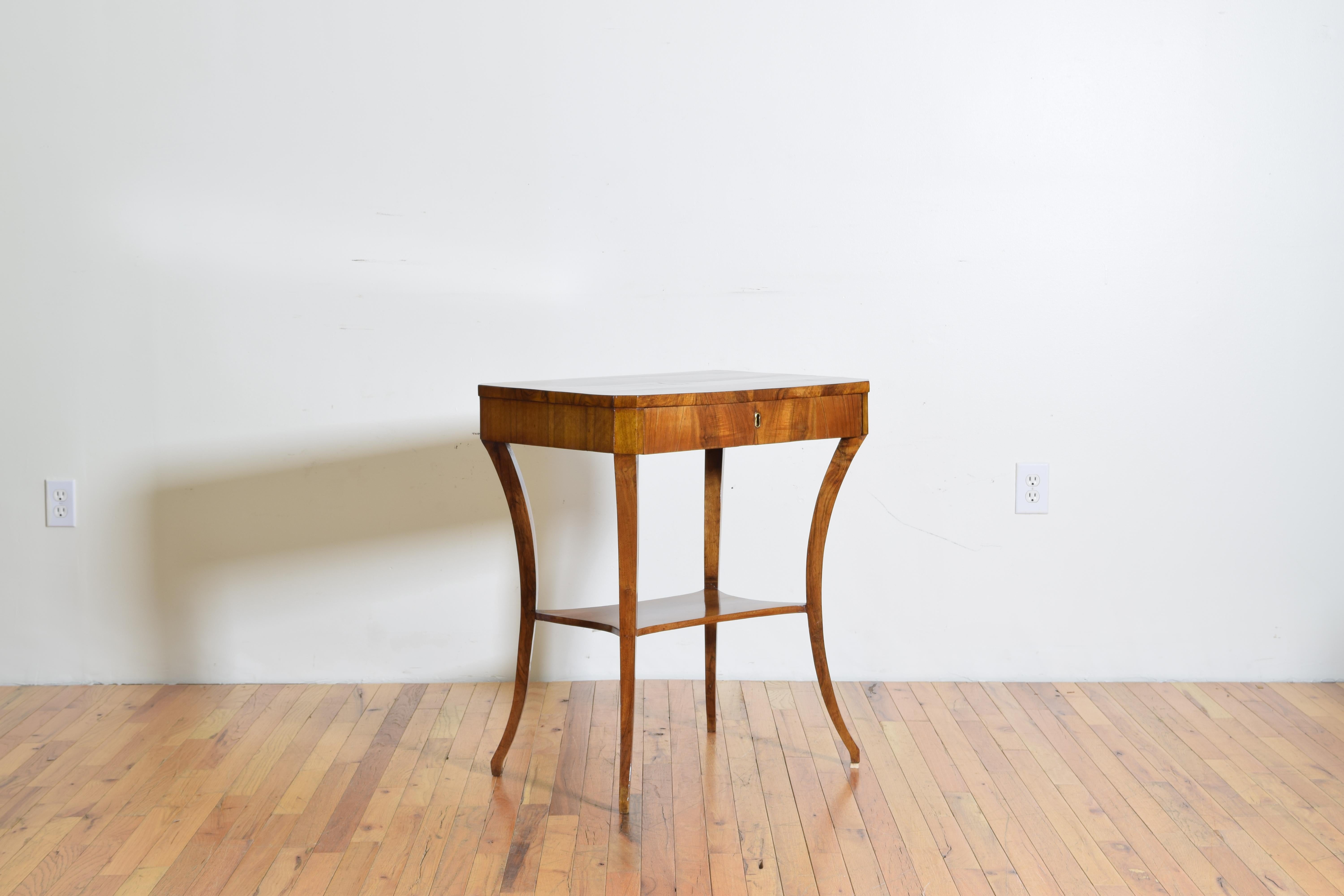 The legs are solid walnut while the case and top are walnut veneer, the top with book-matched veneers, the overall rectangular top with angled corners forming a slight octagonal shape, the conforming case housing one drawer and raised on saber legs