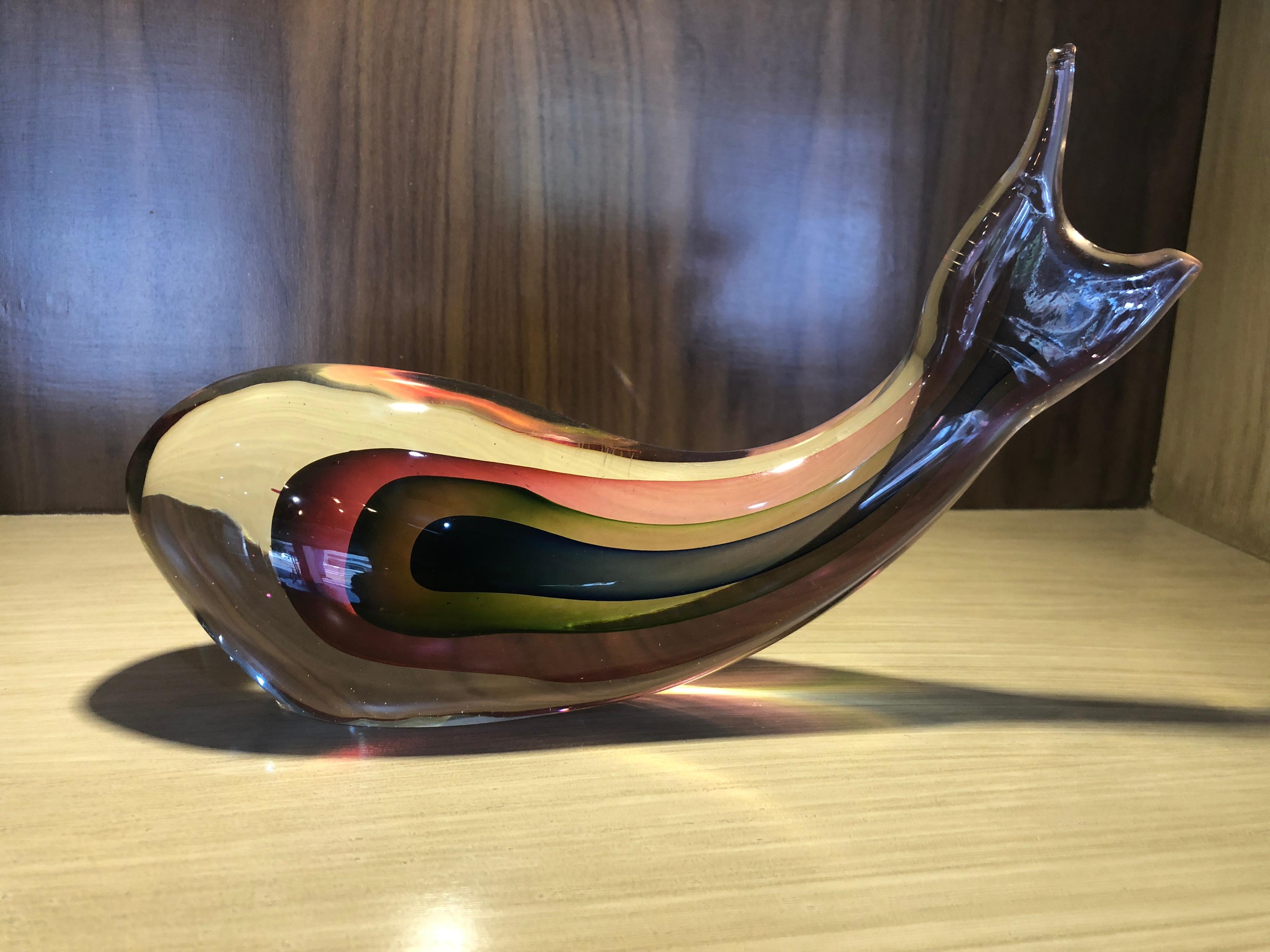 A work of art of Murano sculpture in the shape of a whale, beautiful colors inside, small label below that says 