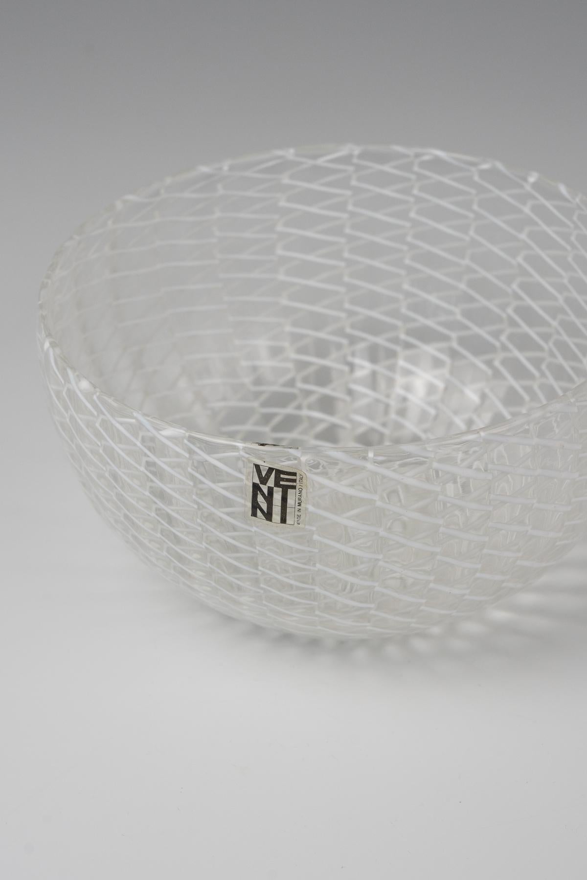 Ciotola in vetro italiano Venini incolore con nastro a zig-zag 

Forma rotonda, ciotola in vetro soffiato a mano italiana Venini Mid-Century modern, pareti in vetro incolore a coste, interno decorato con un sottile nastro bianco a zig-zag che