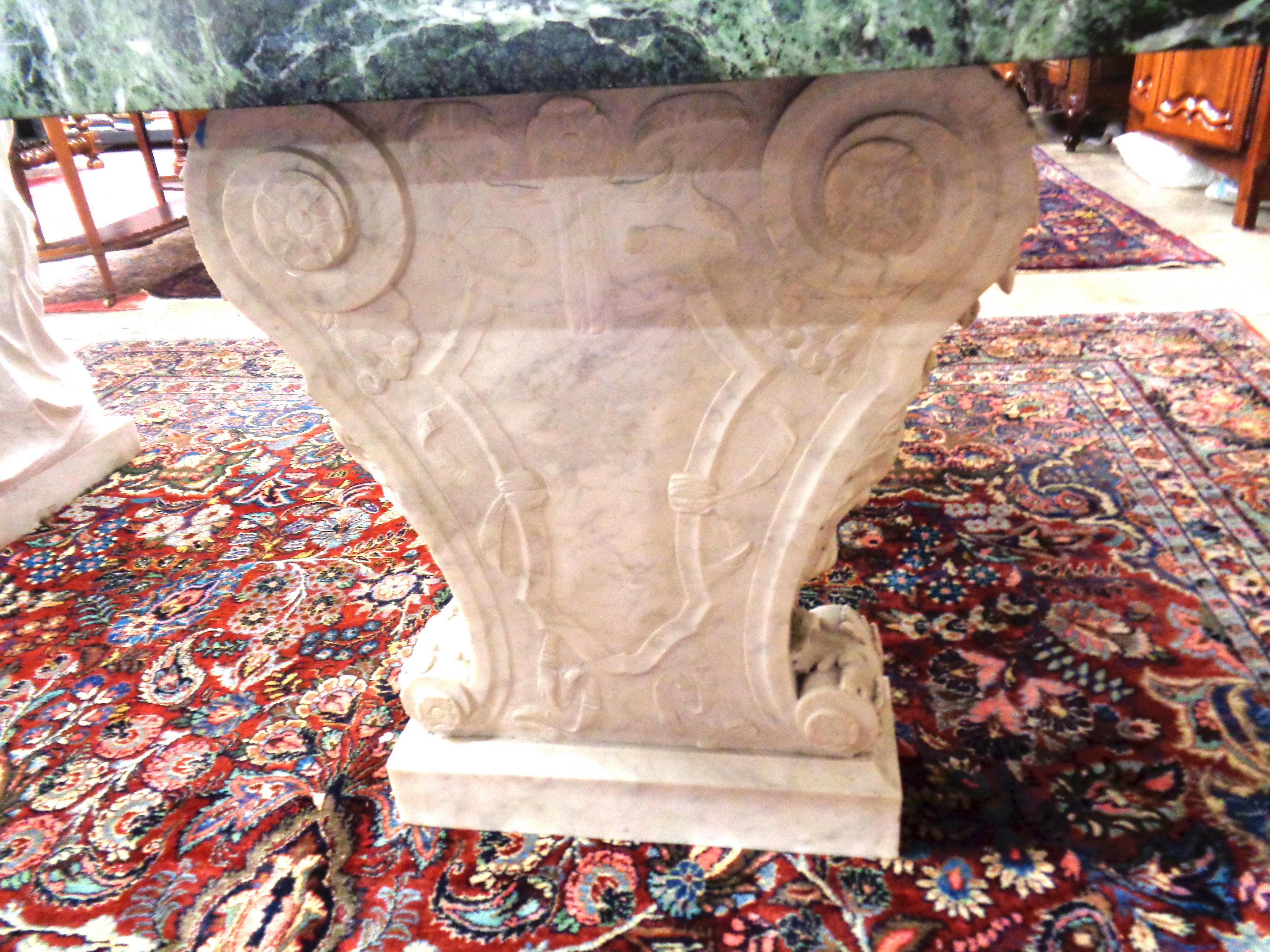 This fine Italian 19th century center/console table has a 2 1/2” thick verde marble top. It is supported by two beautifully carved lyre Carrara marble plinth bases having carved allegorical faces and scrolled acanthus leaves on the front of each