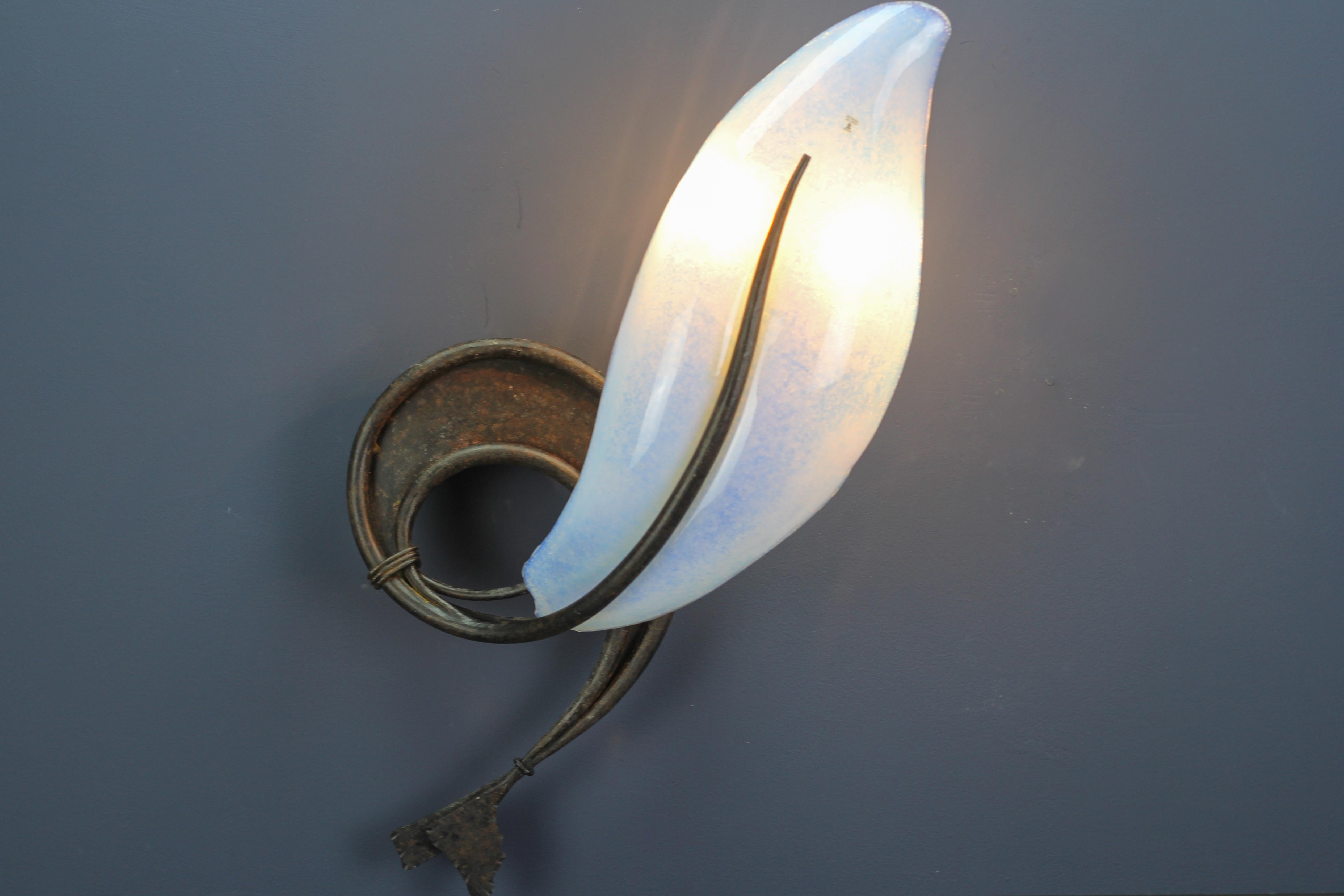 Italian Vetro Murano Venezia opalescent glass and wrought iron wall light from the late 20th century.
This imposing Italian two-light wall lamp features a beautiful opalescent Murano glass lampshade in a shape of a shell or another sea creature and