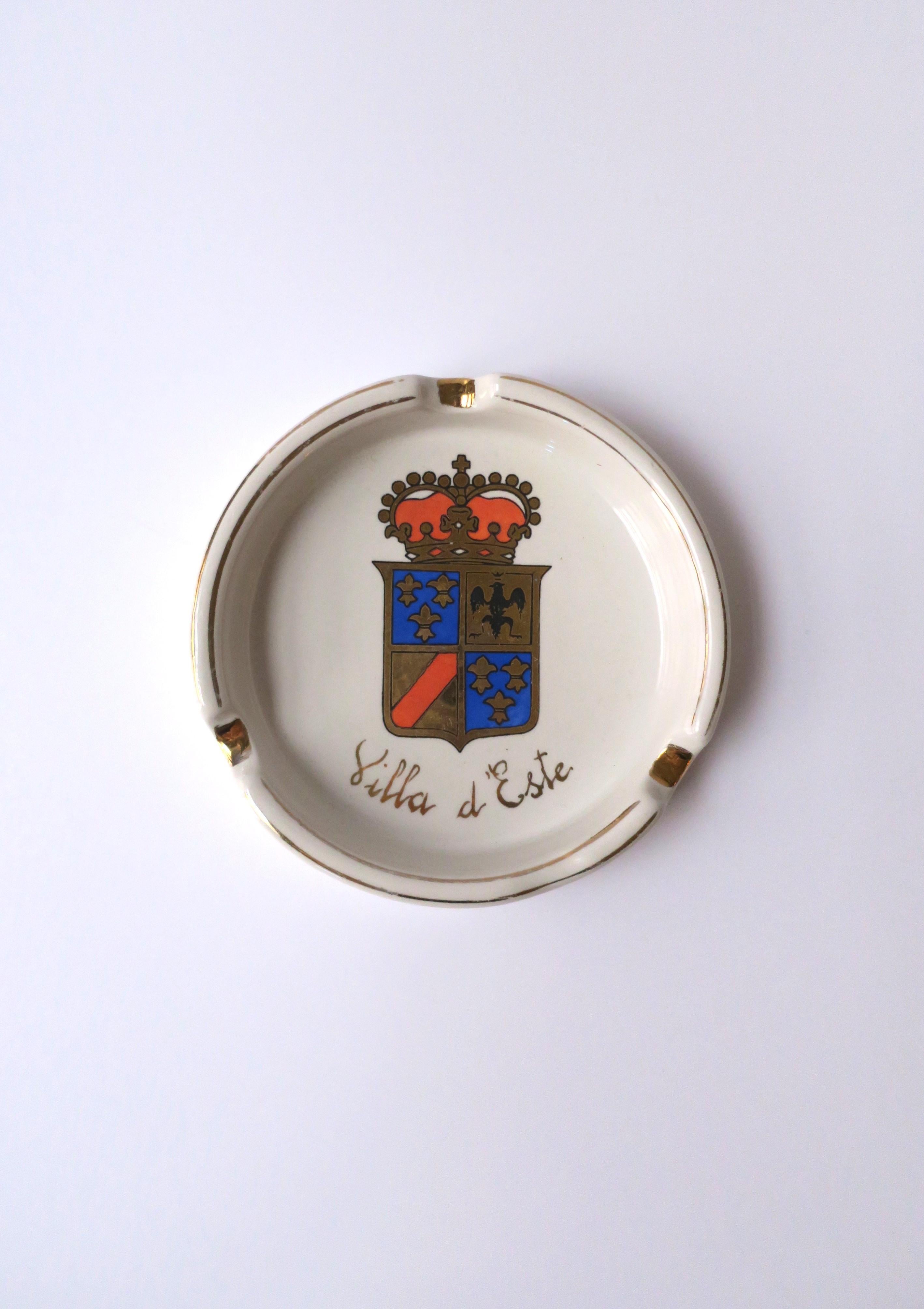 A white ceramic ashtray or catchall vide-poche from the iconic Villa d'Este Hotel, Italy, circa mid-20th century, Italy. Piece is from the iconic Villa d'Este Hotel, Lake Como, northern Italy. Hotels' crest at center in black, gold, royal blue and