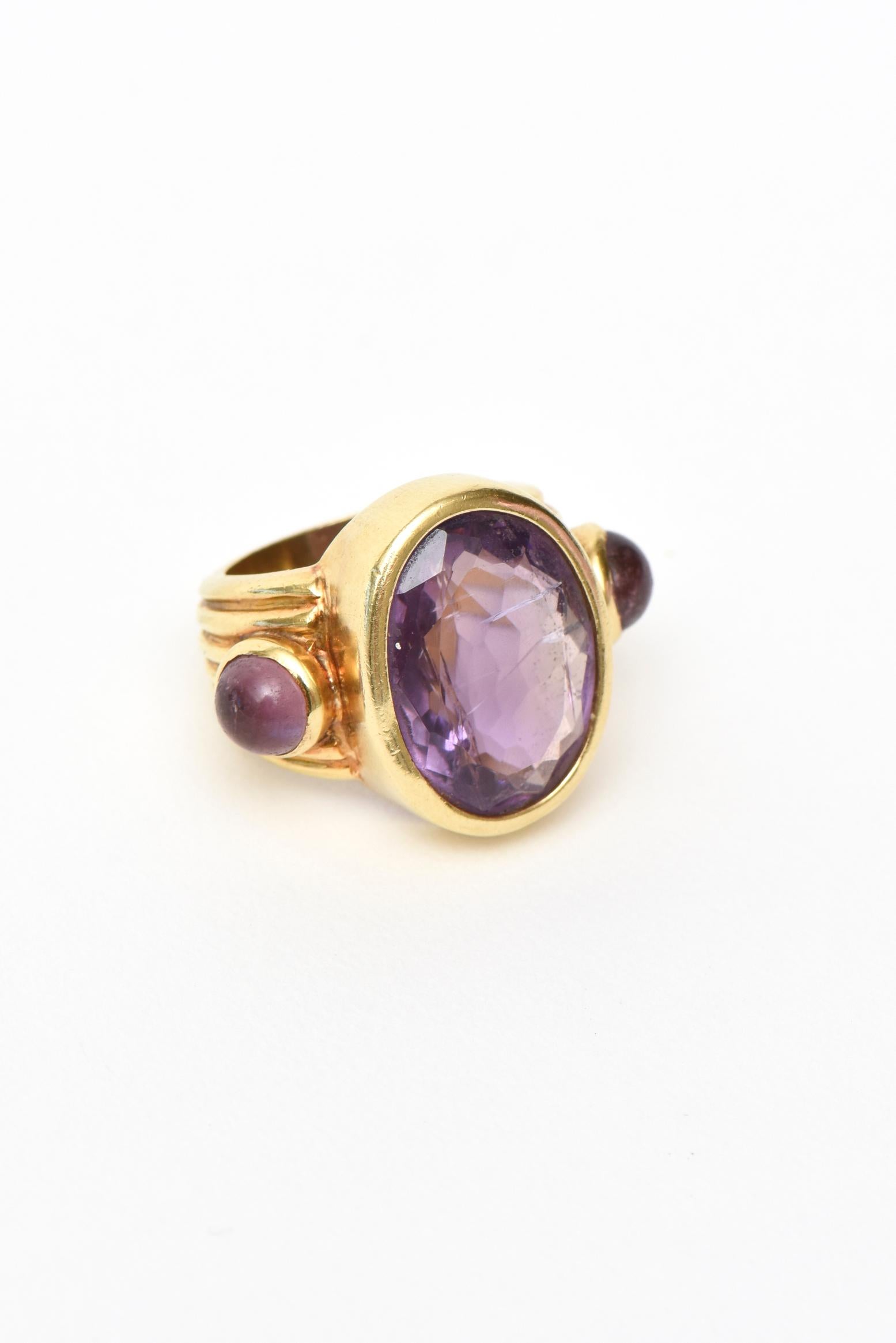 This well made and beautiful vintage Italian 18K Gold and amethyst ring has 2 cabochon amethyst stones on the side. It is unsigned and the ring size is 5.5. It has bands of lines of 18K gold on the sides and back. Finely made. The weight is approx.