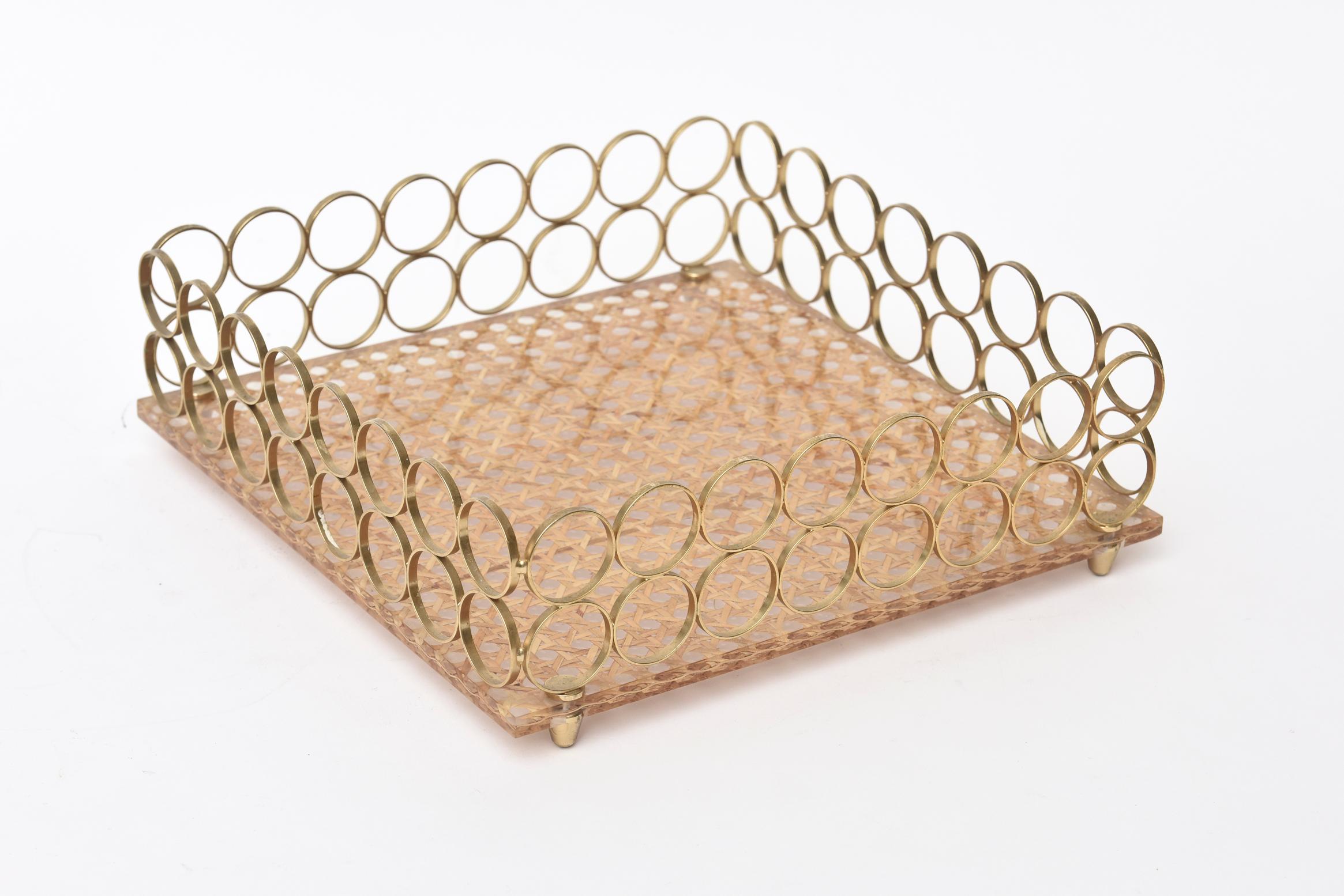 This lovely vintage Italian square tray has 2 rows of circles of brass as the borders and a caned base with a Lucite top. It is from the 1970s. It has 4 peg feet. Great for serving, for barware or for decoration. The uses are for many applications.