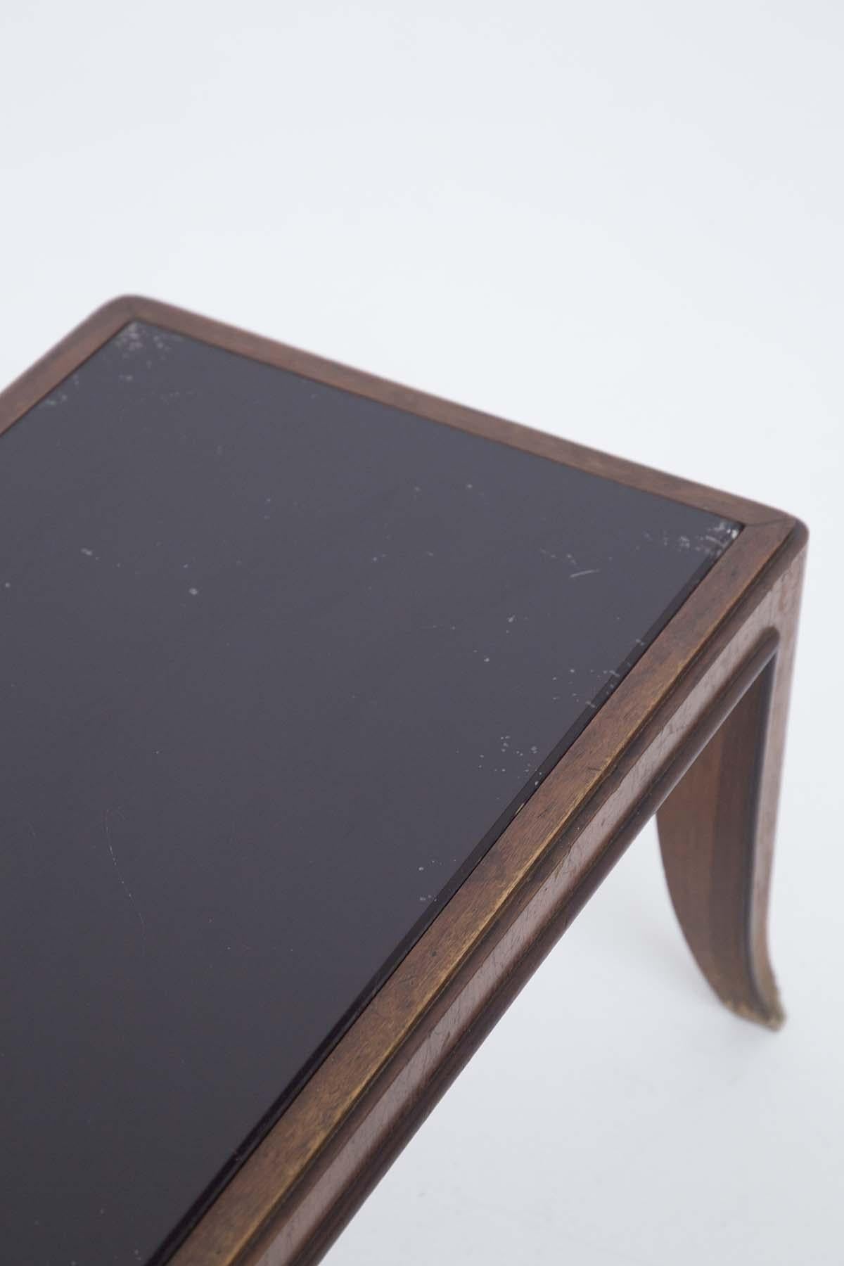 Table basse attribuée à Gio Ponti, conçue dans les années 1950. La table basse a un plateau en verre foncé parfaitement intact. Le cadre est fait de bois très solide. La structure de la table est entourée de finitions en bois de bonne facture. La