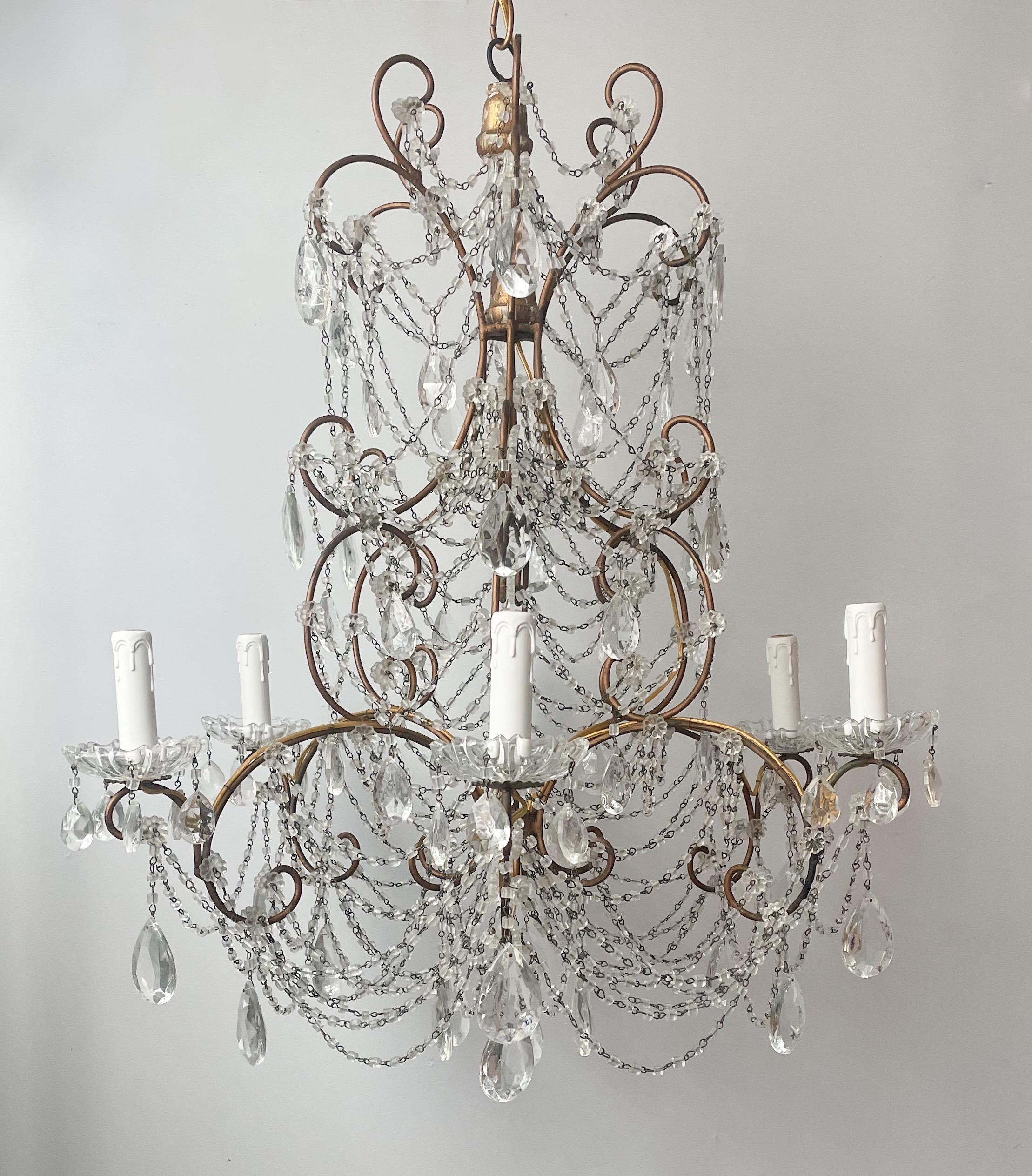 Glorious, Italian 1940s gilt-iron and crystal beaded chandelier in the Louis XV style.

The chandelier consists of a elaborately scrolled iron frame with a hand-applied gilt finish and a bounty of “macaroni” glass beads. 

The chandelier is