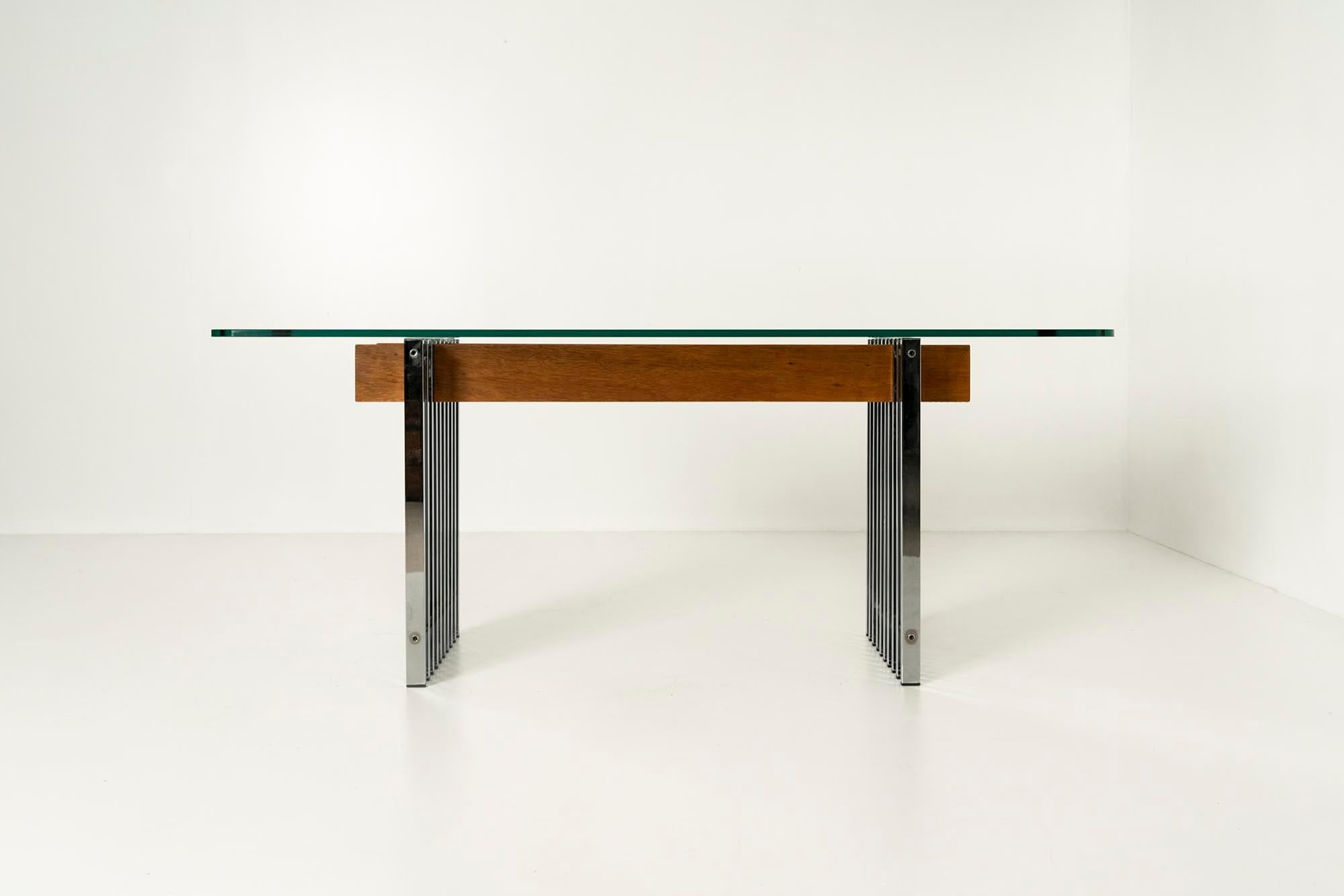 In this beautiful 1970s Italian dining table, the materials of wood, metal, and glass are combined in a pleasant proportion. The metal legs of the table consist of a construction of ten linked bars. In the middle, we see two well-proportioned teak