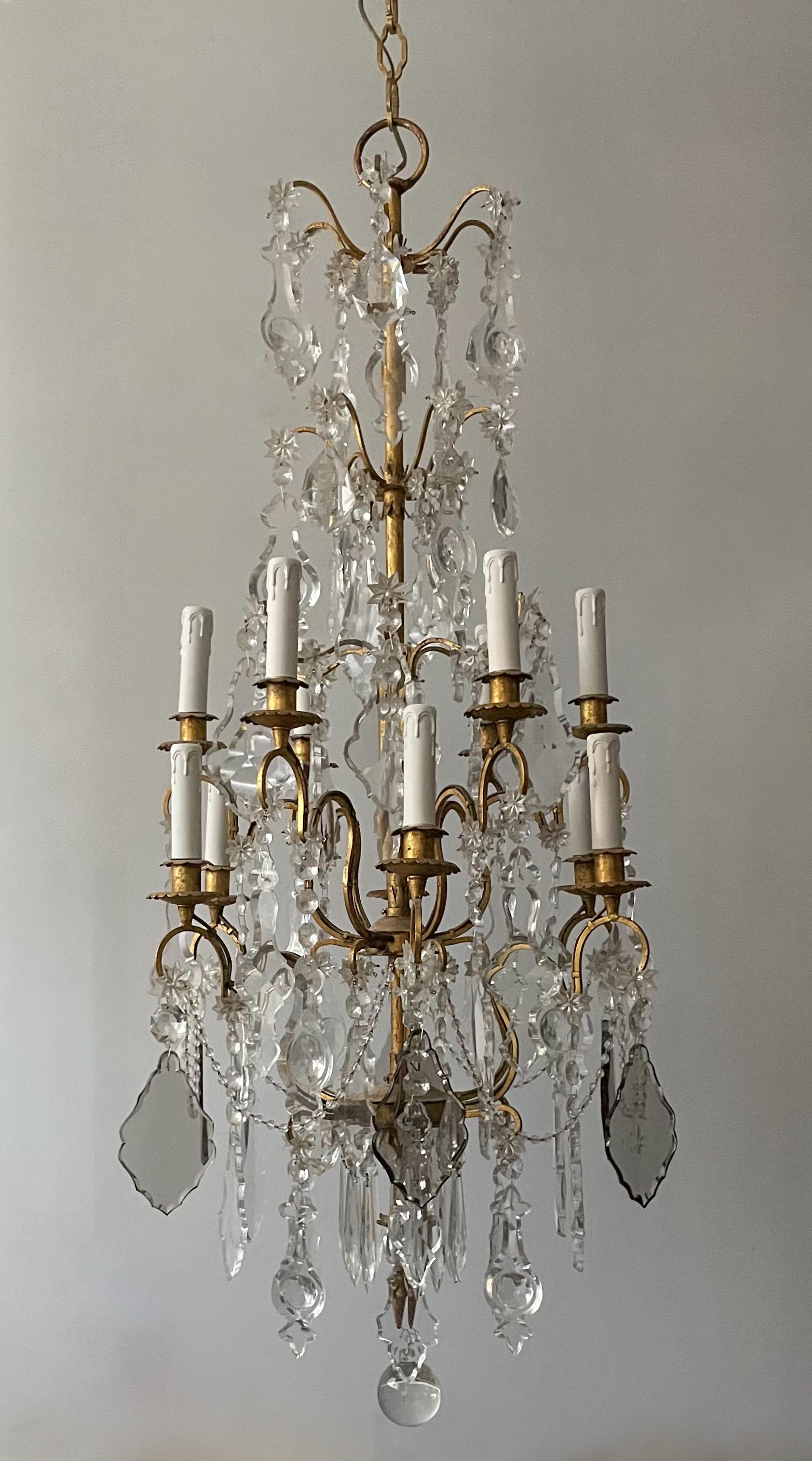 Superbe lustre italien des années 1940 en fer doré et cristal de style néoclassique.

Le lustre se compose d'un cadre en fer doré à deux niveaux, décoré d'une riche abondance de pendentifs français aux formes harmonieuses. 

Le lustre est câblé