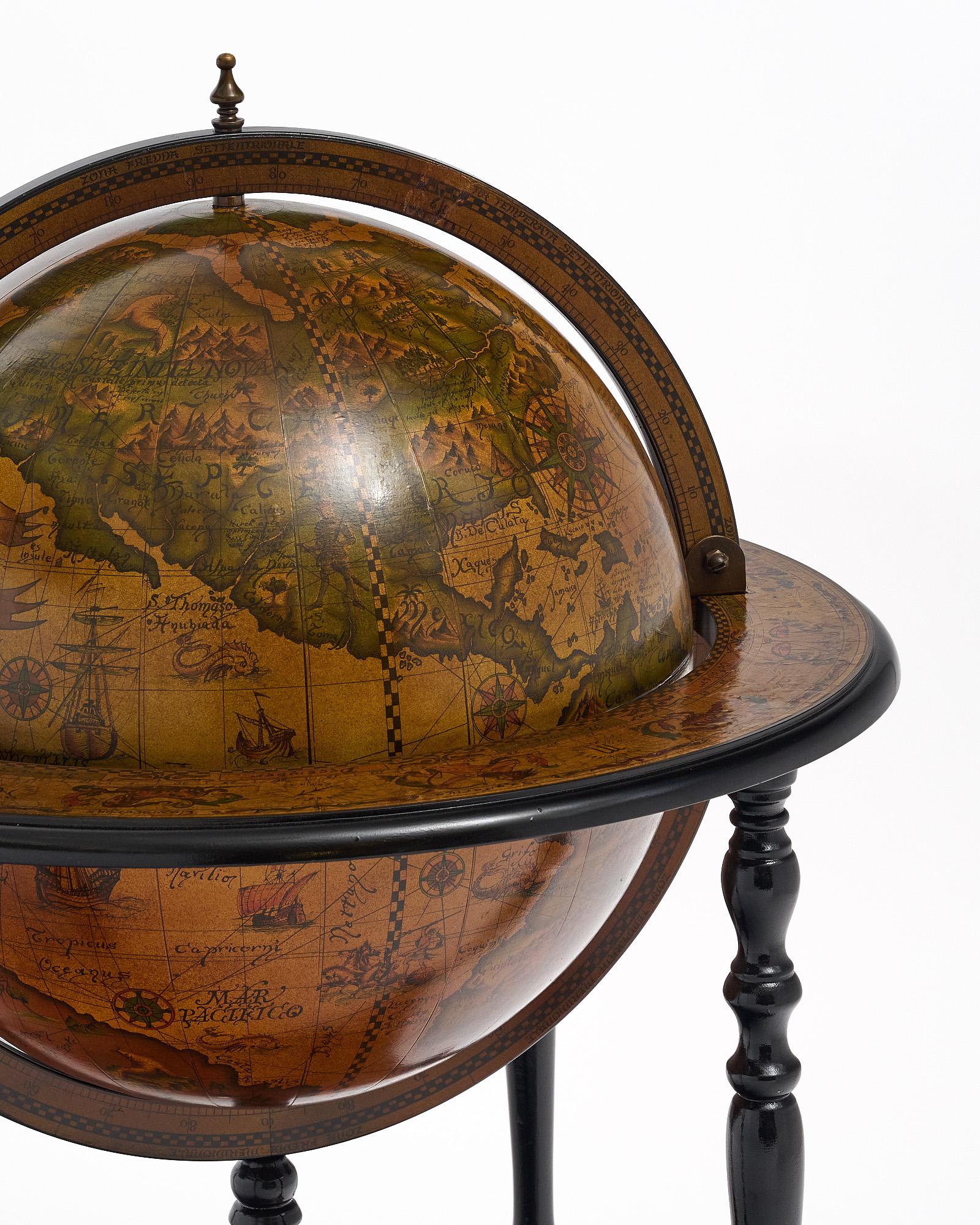 Globe from Italy with hand-painted décor from the 20th century in Italy. The globe rotates and is supported by an intricate, hand-carved ebonized four-legged structure on casters. The globe opens to a fully featured bar with bottle holders. The