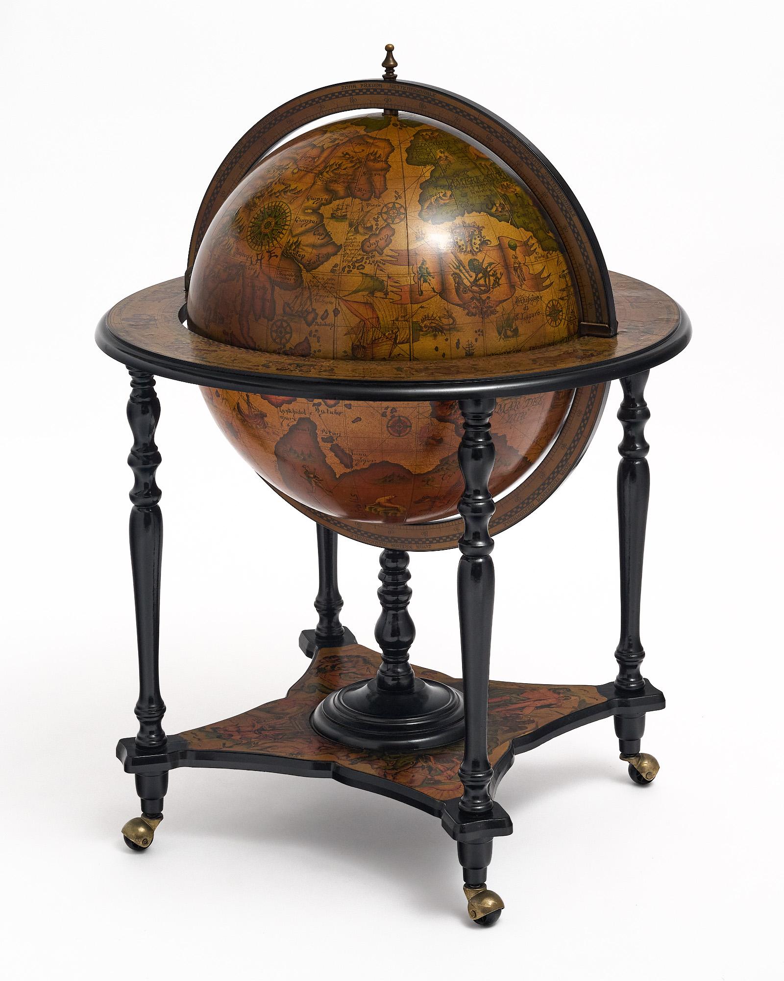 Globe from Italy with hand-painted décor from the 20th century in Italy. The globe rotates and is supported by an intricate, hand-carved ebonized four-legged structure on casters. The globe opens to a fully featured bar with bottle holders. The