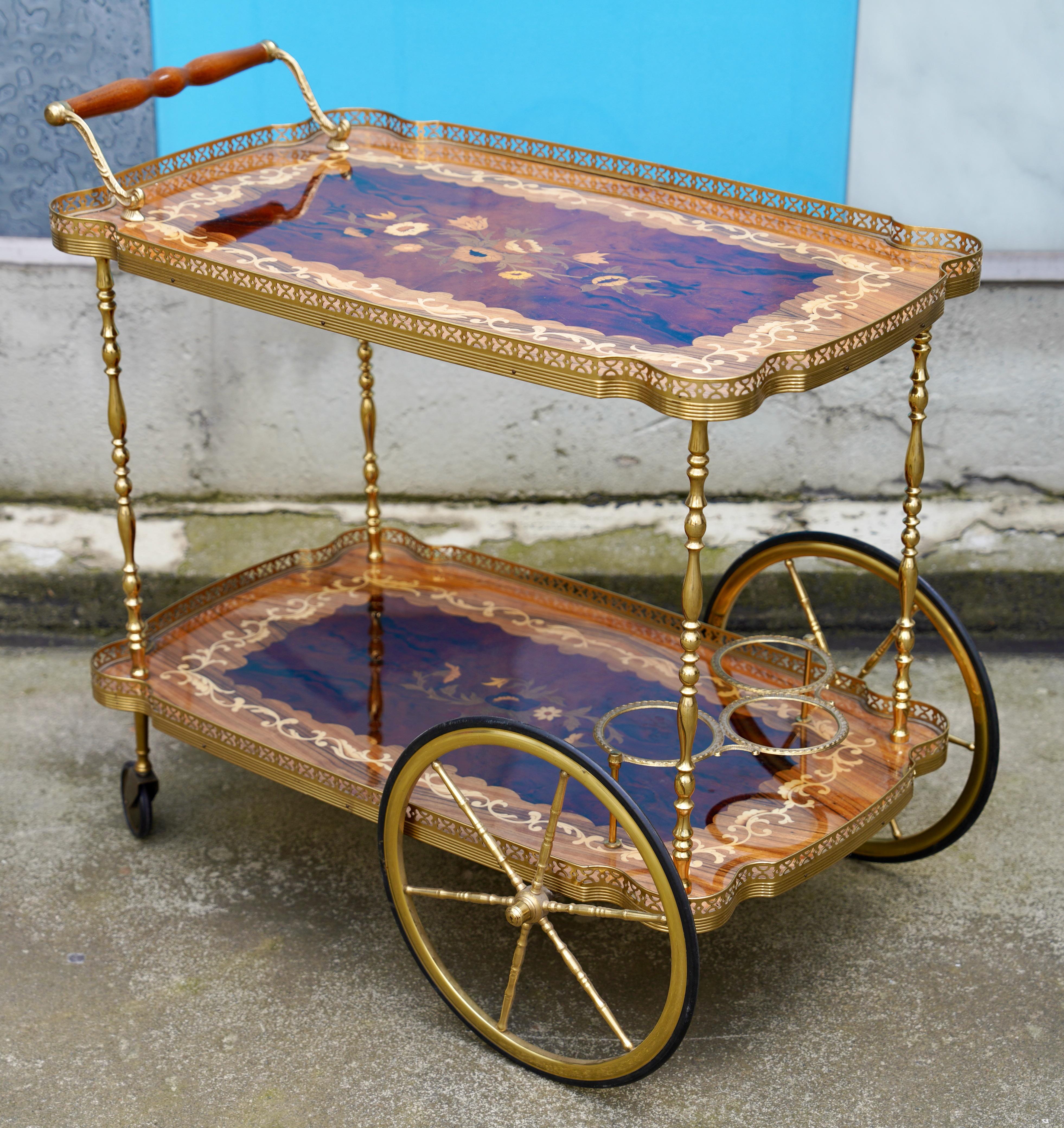 Italian vintage Hollywood Regency wooden inlaid bar cart, circa 1970, serving cart

This exquisite Hollywood Regency style bar cart dates from the 1970s and was made in Italy. It impresses with its elaborate inlay work on the two wooden shelves,
