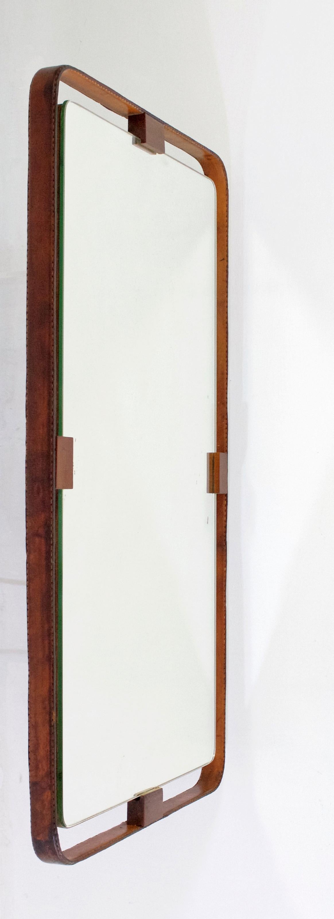 A handmade rectangular wall mirror in a masculine and clean design with a leather frame attached with teak wood to the glass. In very nice vintage condition.