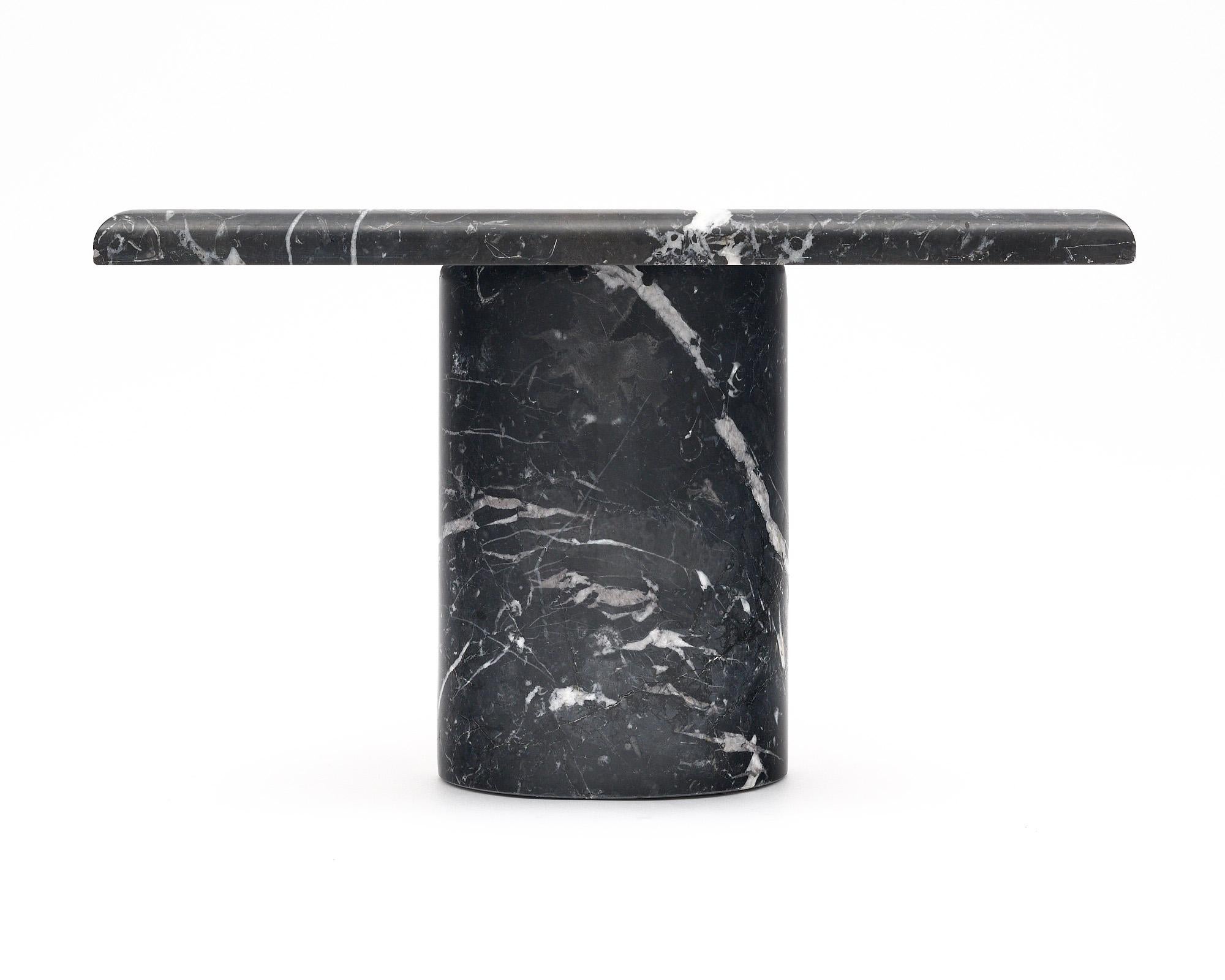 Side table from Italy with a sleek design. This vintage piece is made entirely of black marble with a striking white veining throughout. The cylindrical base holds the square slab top.
