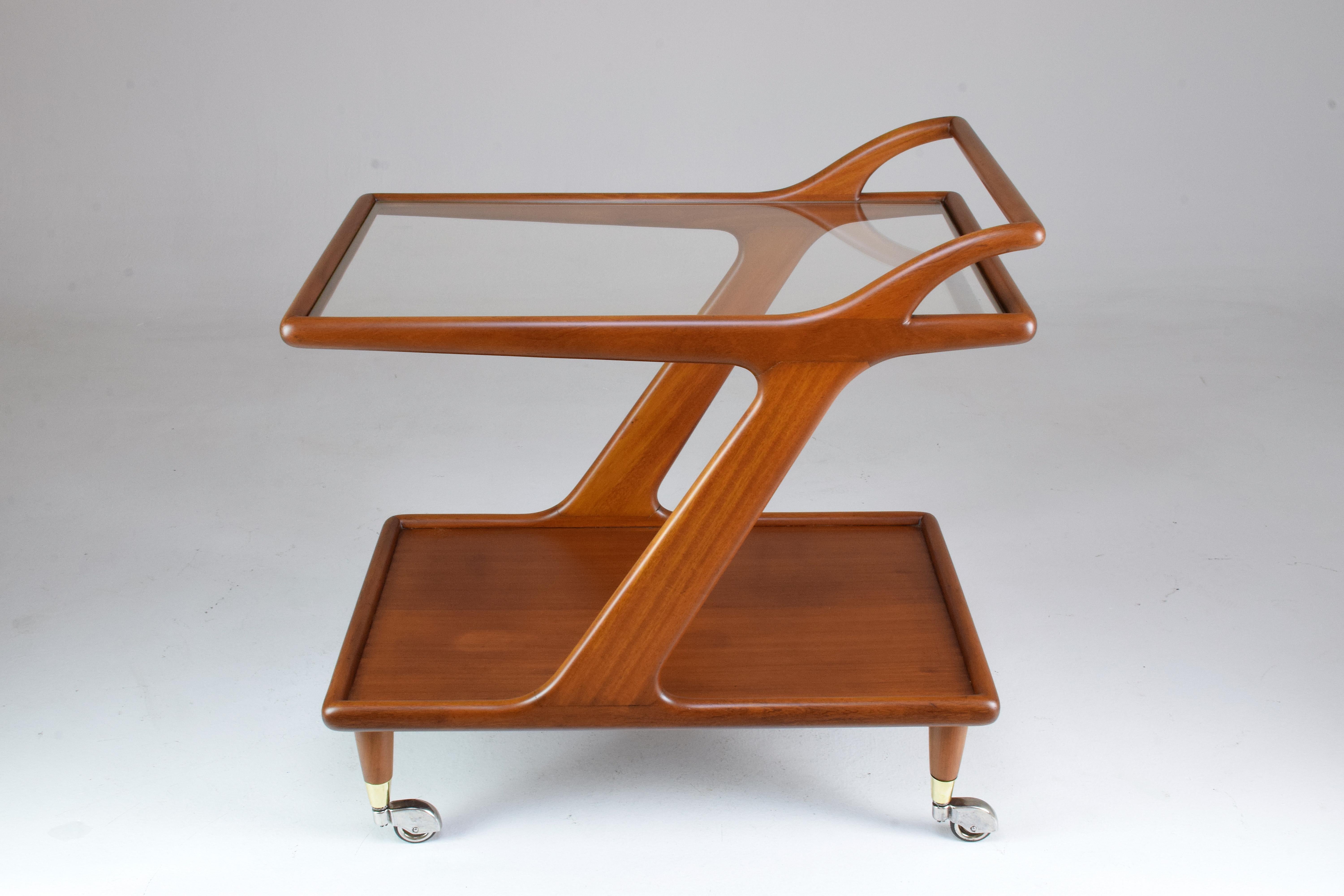A 20th century two-tier bar or serving cart on its original rollers with glass tabletop and light walnut structure with a curved handle typical of the Italian design period.
Italy, circa 1950s. 

All our pieces are fully restored at our atelier