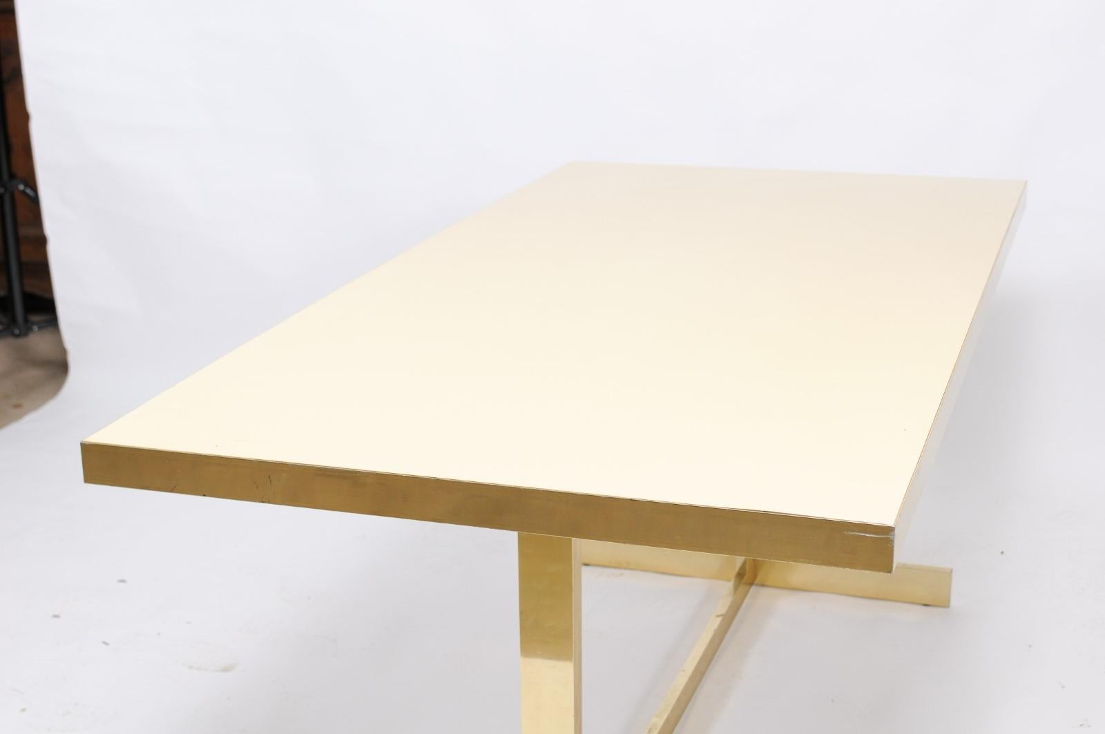 A vintage Italian dining table from the mid-20th century, with formica rectangular top and brass trestle base. This stately Mid-Century Modern Italian vintage table has some minor scratches from age on the formica, but we don’t think it deters from