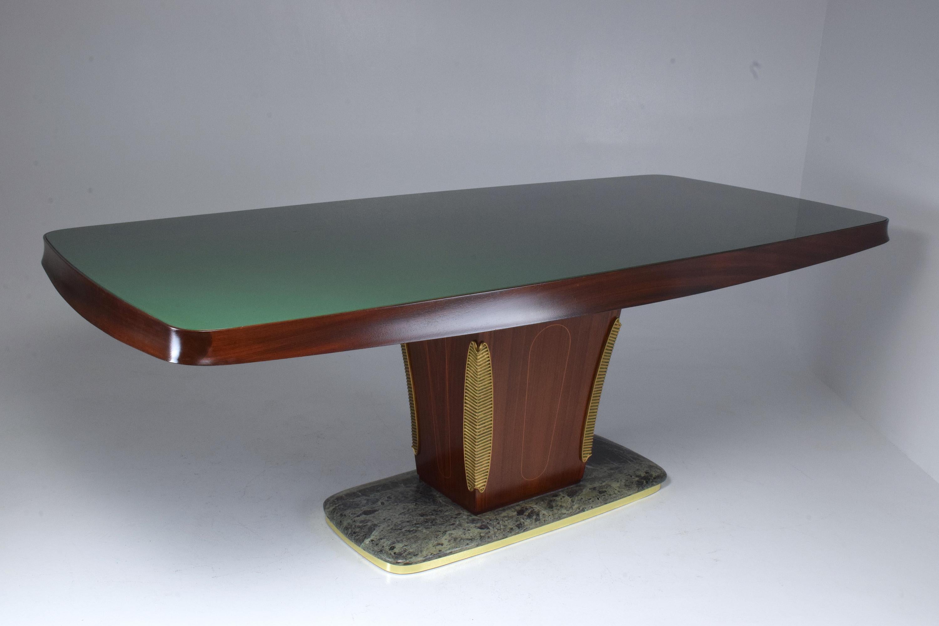 A 20th century vintage eight seating dining table designed by the Italian Vittorio Dassi, circa 1940s-1950s. The exceptional woodwork is highlighted by the curved green glass top and rounded edges of the structure. This Art Deco style piece is