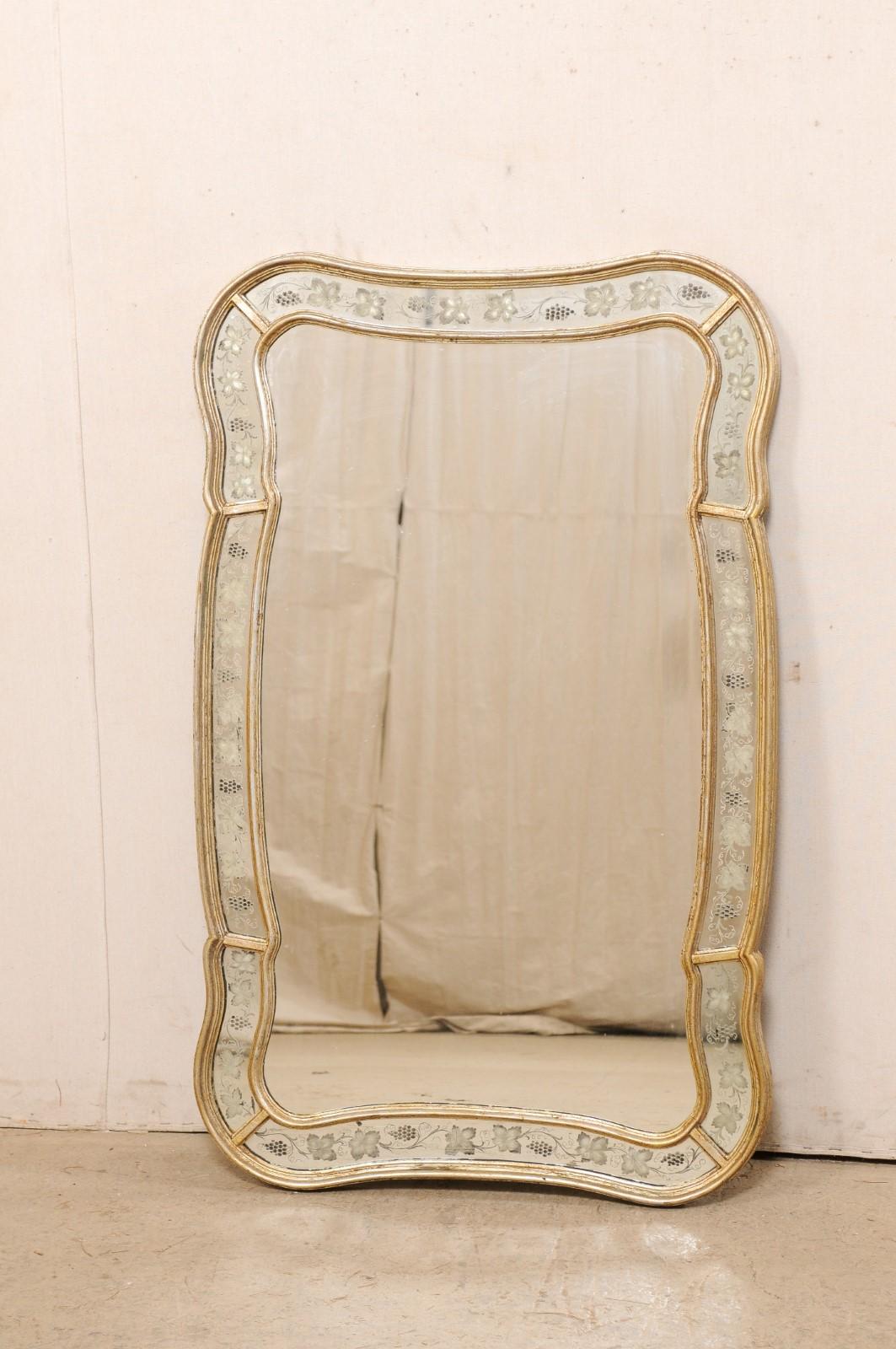 A shapely Italian mirror with grapevine motif surround, standing approximately 4 feet in height. This vintage mirror from Italy has a mostly rectangular shape, but more curvy and softened with gentle scalloping. The inner mirror is framed within a