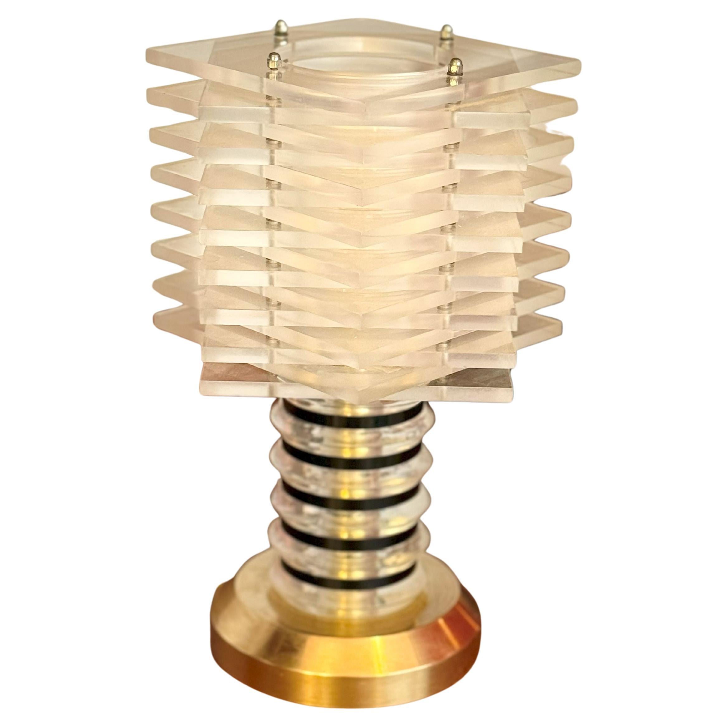 Rare lampe de table compacte de la période moderniste italienne de la fin des années 1960-70, combinant Lucite et laiton poli dans une forme architecturale.

L'abat-jour architectural est composé de lames de Lucite horizontales empilées, créant un