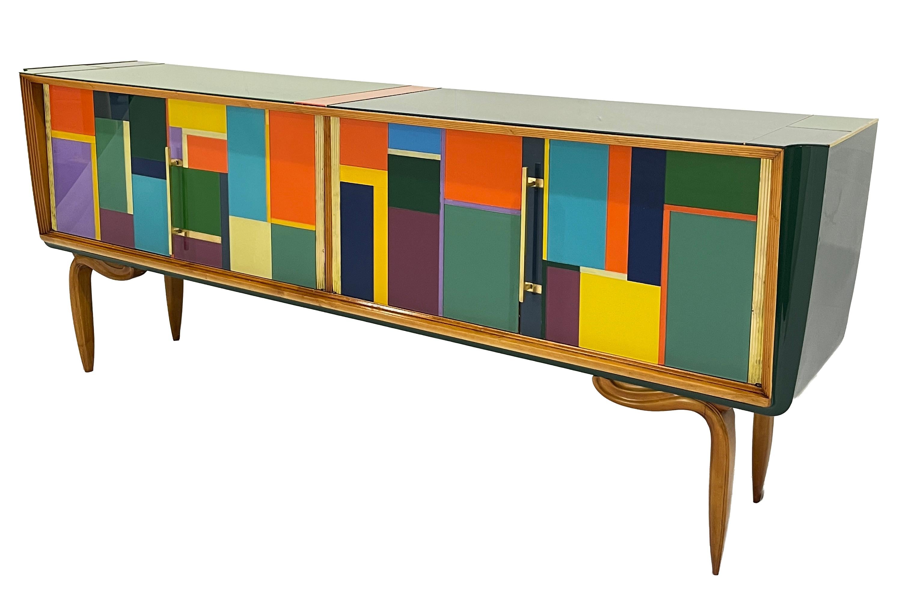 Vibrante celebración del diseño italiano de mediados de siglo, este exquisito mueble buffet de los años 50 con 4 puertas capta el espíritu de la estética Mondrian a través de una magistral composición de paneles de cristal aplicados a mano en la