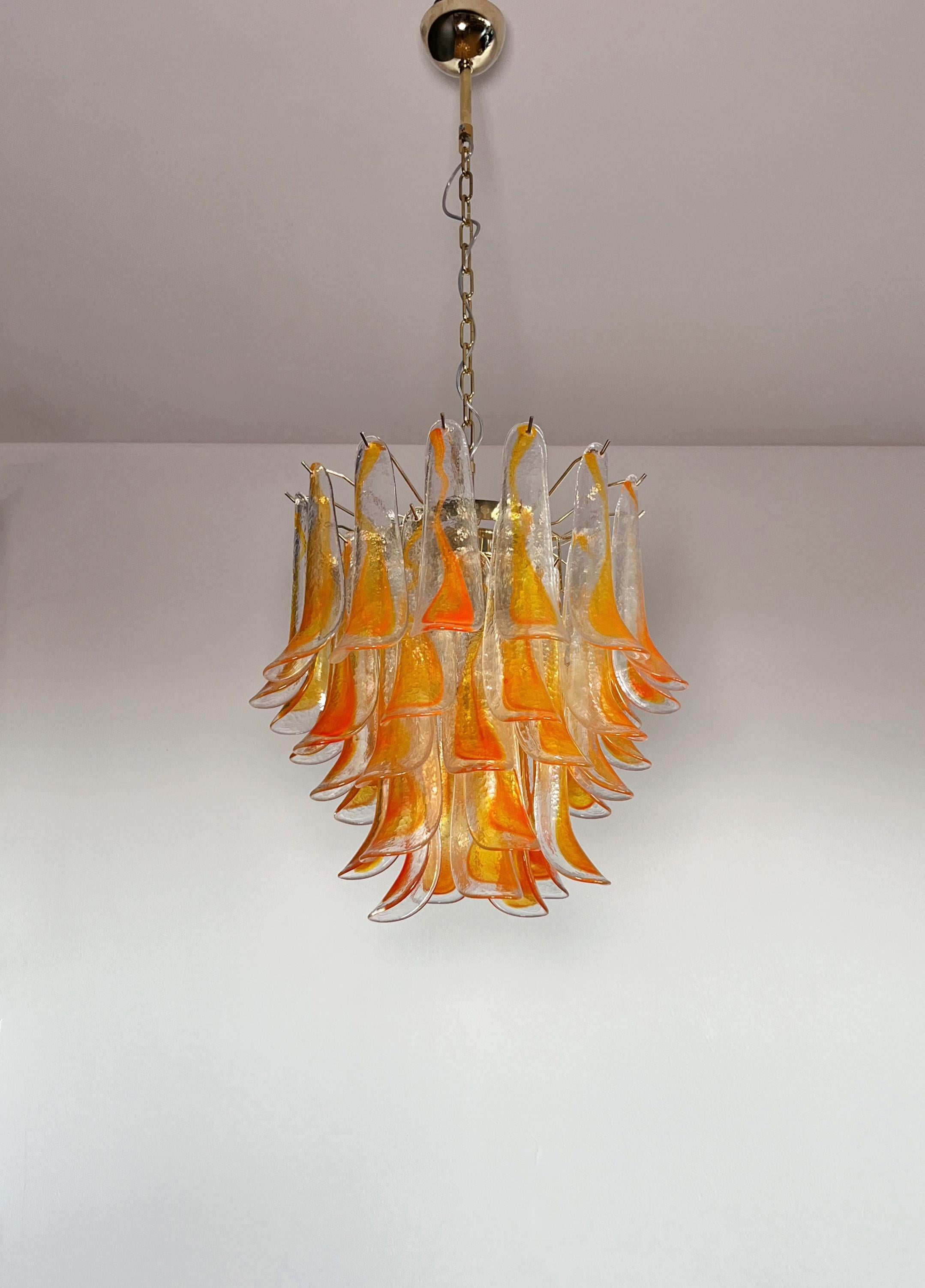 Huge Italian vintage Murano chandelier made by 41 glass petals (transparent and orange) in a brass plated metal frame. The structure has been perfectly restored, therefore in excellent condition.
This chandelier is a unique piece, glass created for