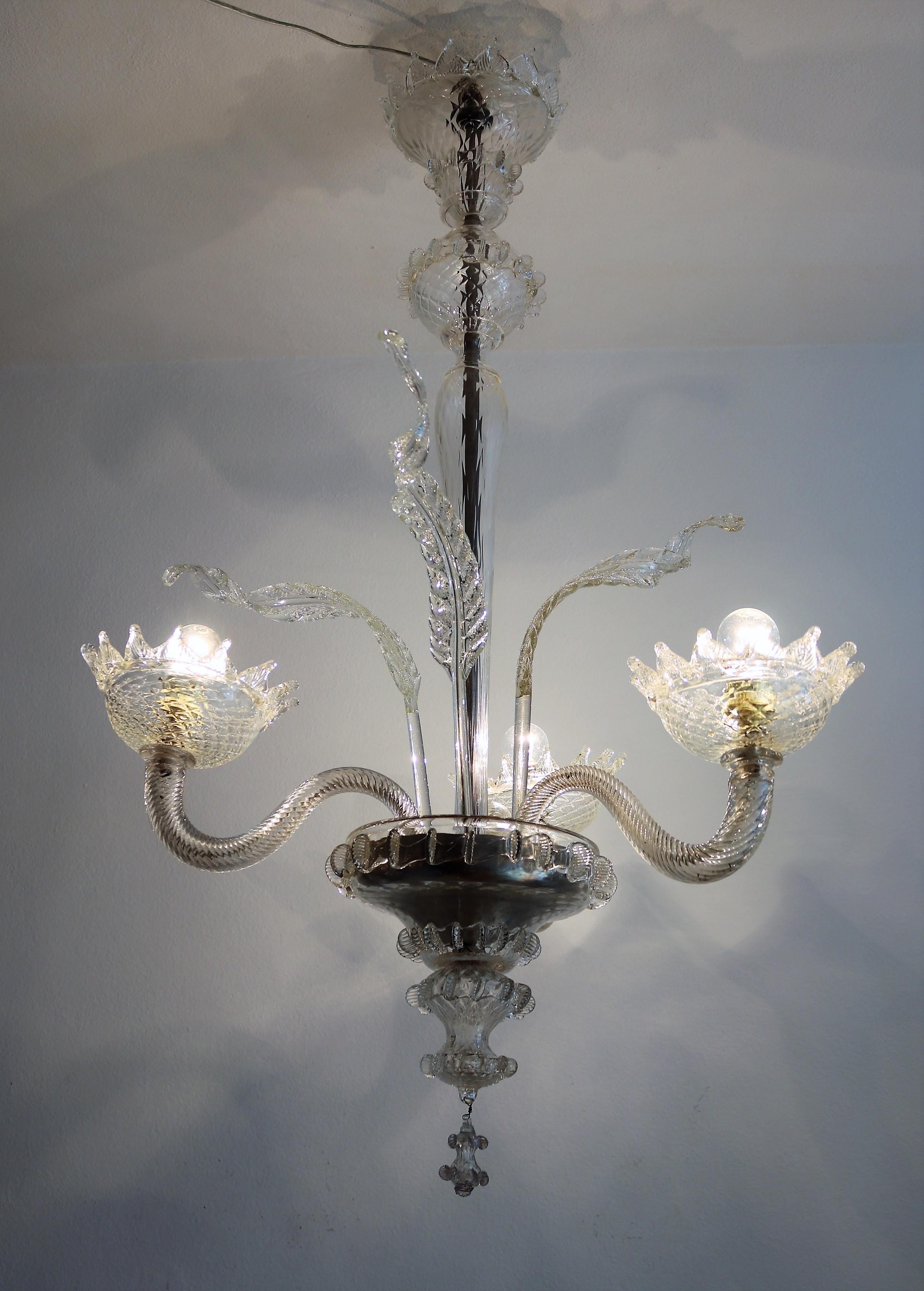 Beautiful true vintage chandelier with up-going arms and light bulbs inside beautifully handcrafted glass bowls.
Made in Murano, Italy, during the 1950s.
The chandelier is in transparent color with light shades of off-white - cream in some