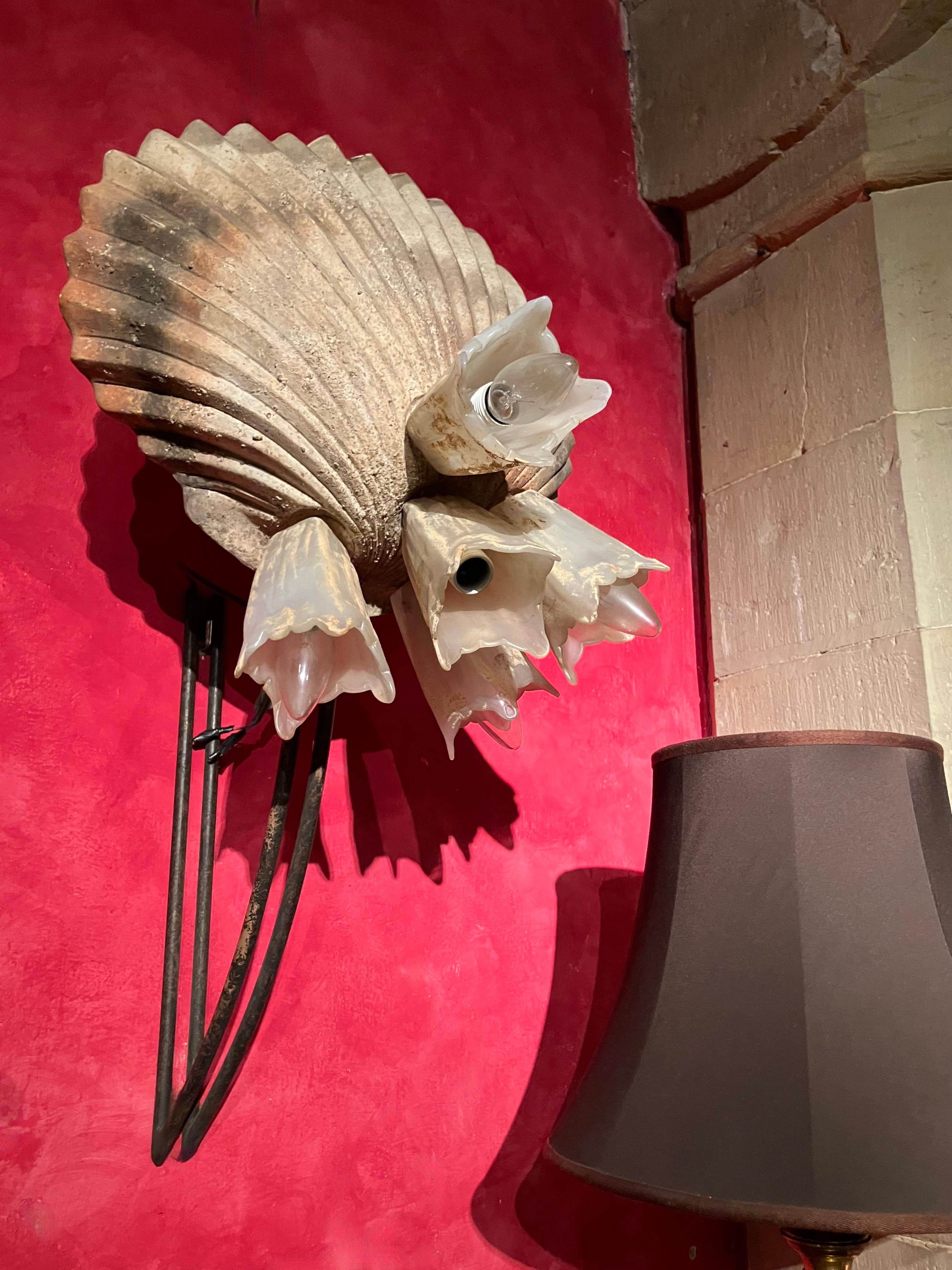 Questa impressionante lampada da parete vintage italiana, disegnata da Sergio Terzani negli anni '80, incarna lo stile moderno organico con influenze brutaliste. Caratterizzato da una grande base a conchiglia in terracotta lavorata a mano, ornata da
