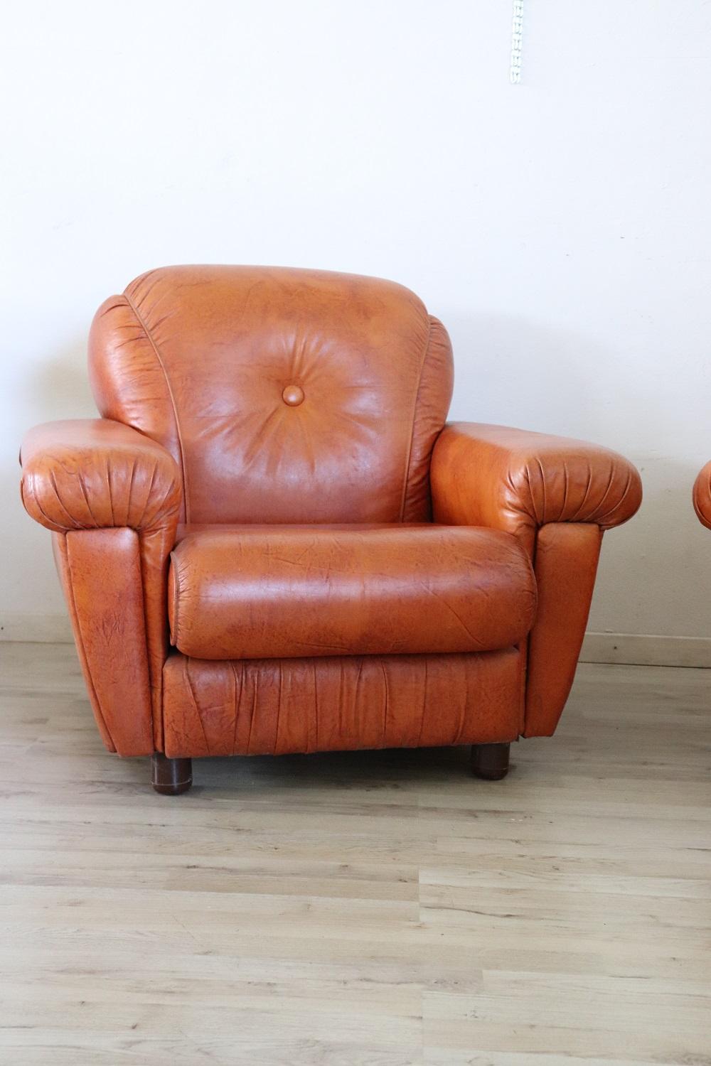 Beautiful 1980s pair of armchairs with a orange faux leather. These loving armchairs have a comfortable seat. Vintage good conditions.