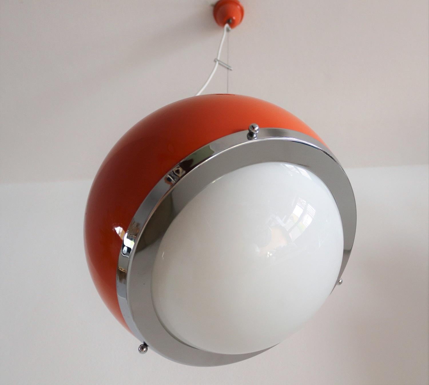Very particular pendant lamp from the Space Age with aluminium base in shiny orange and curved opaline glass plate.
Made in Italy during the 1960s.
It is a special feature of the lamp that it is possible to adjust the inclination of it by changing