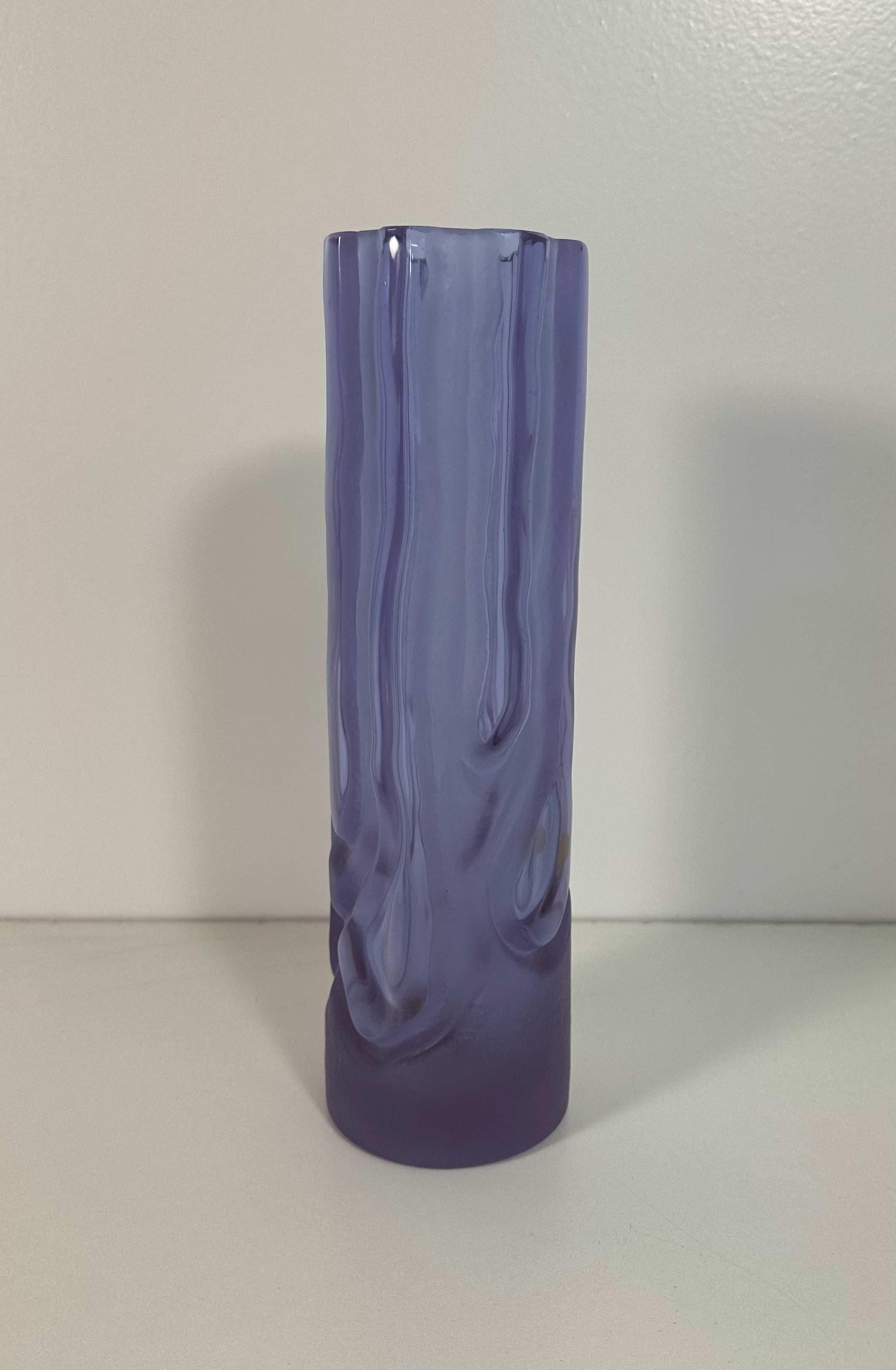 This Violet Vase was produced in Murano, Italy in the 1970s It is made with a particular glass working technique called 'Satinato', which means 'frosted glass'. 
It changes its color with different lighting (it may look blue under some kind of