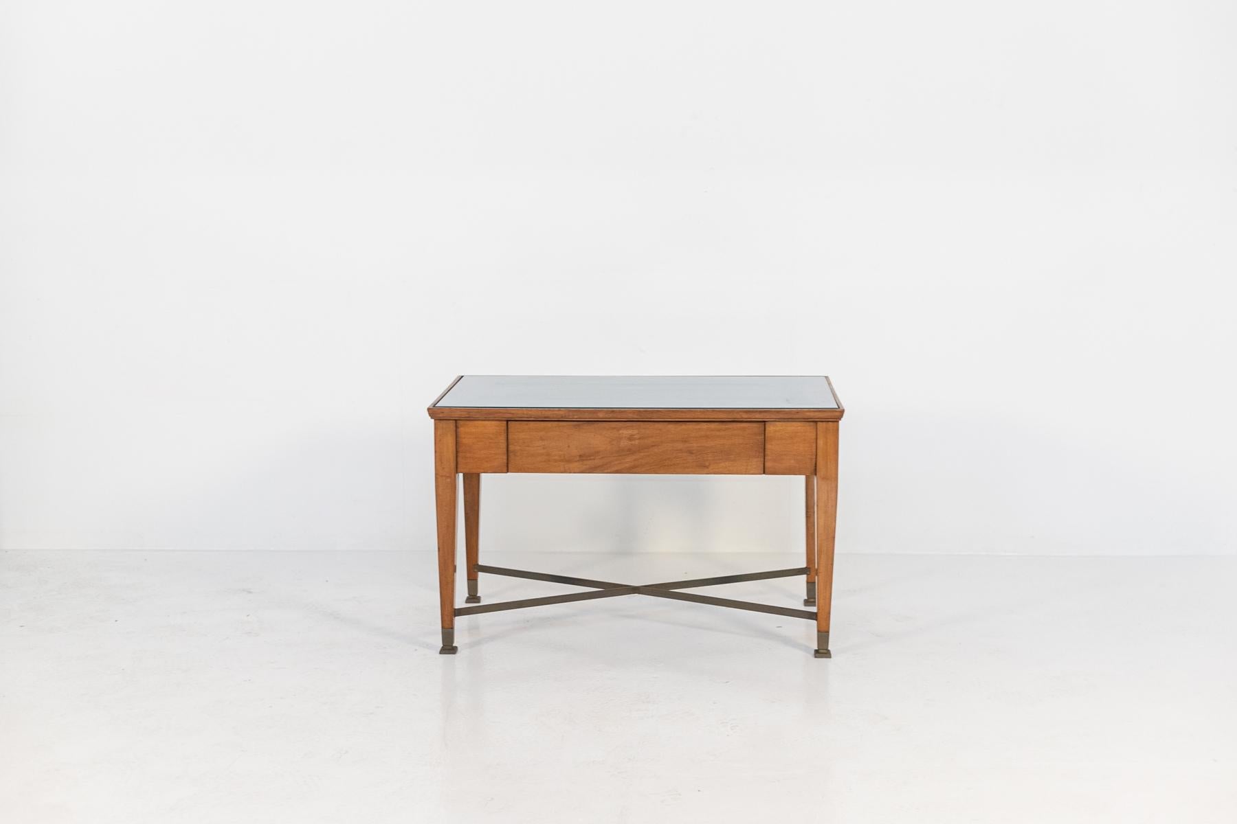 Low Italian wooden coffee table attributed to Gio Ponti from the 1960s. The coffee table has a wooden structure with rigorous and clean shapes. The four legs of the table are connected by central brass X-shaped bars. The feet have square brass