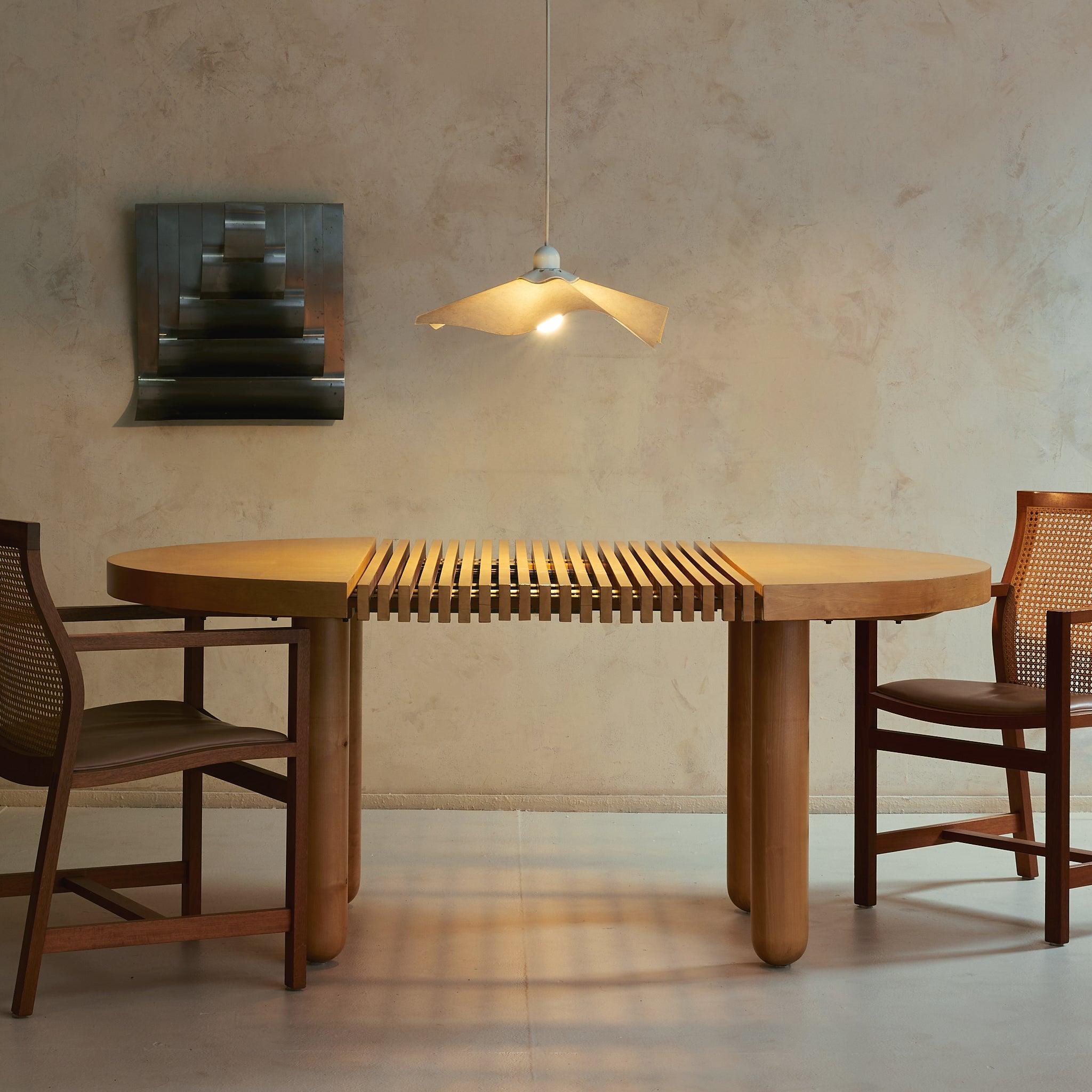 An Italian sculptural dining table of rare craftsmanship—at once architectural and deeply tactile. Thoughtfully conceived and exquisitely built, this piece invites both admiration and everyday use. Its oval form unfolds around a central panel of