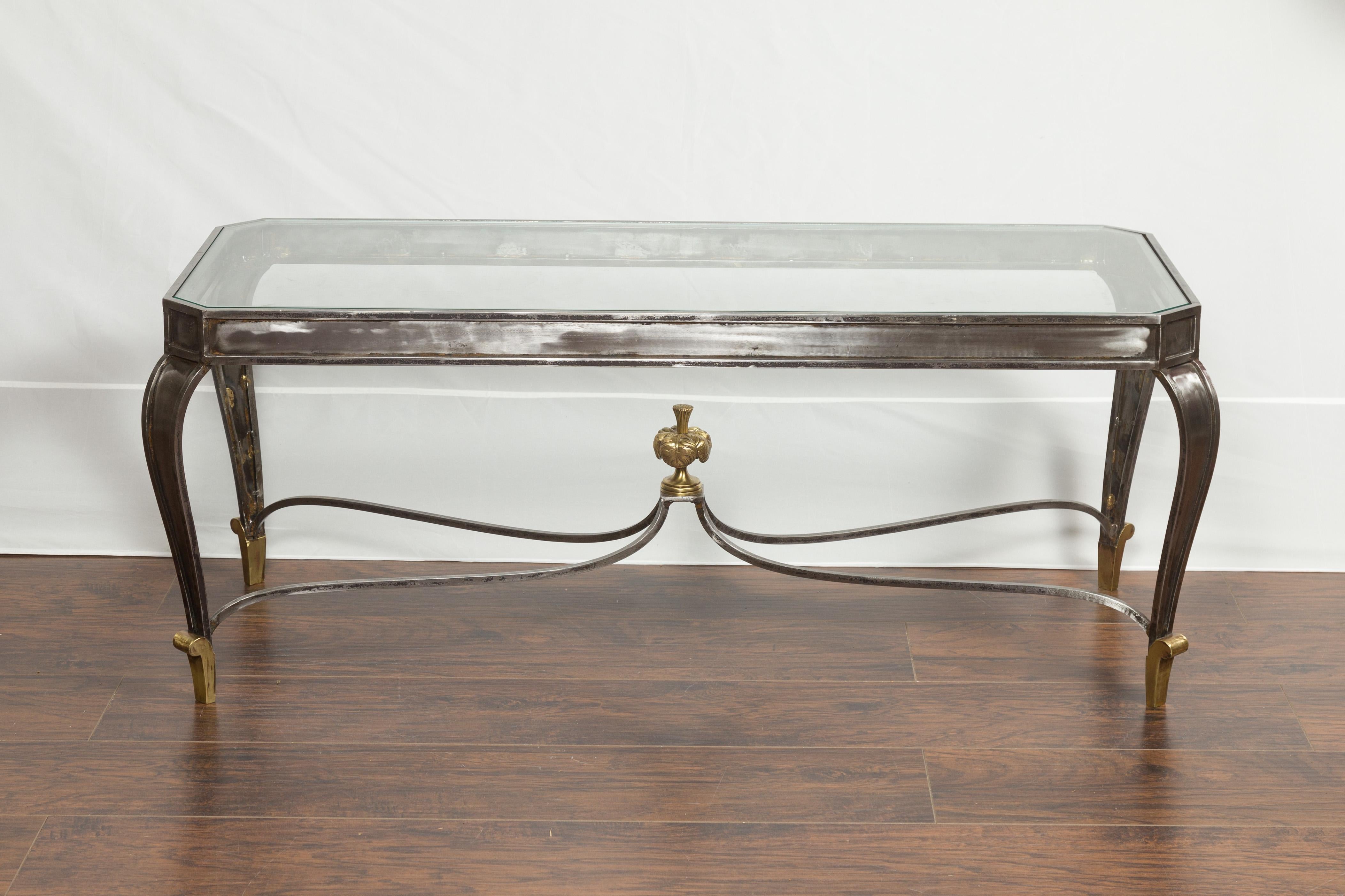 An Italian vintage steel and bronze coffee table from the mid-20th century, with glass top and feathery style finial. Created in Italy during the midcentury period, this coffee table features a rectangular glass top with canted corners, sitting