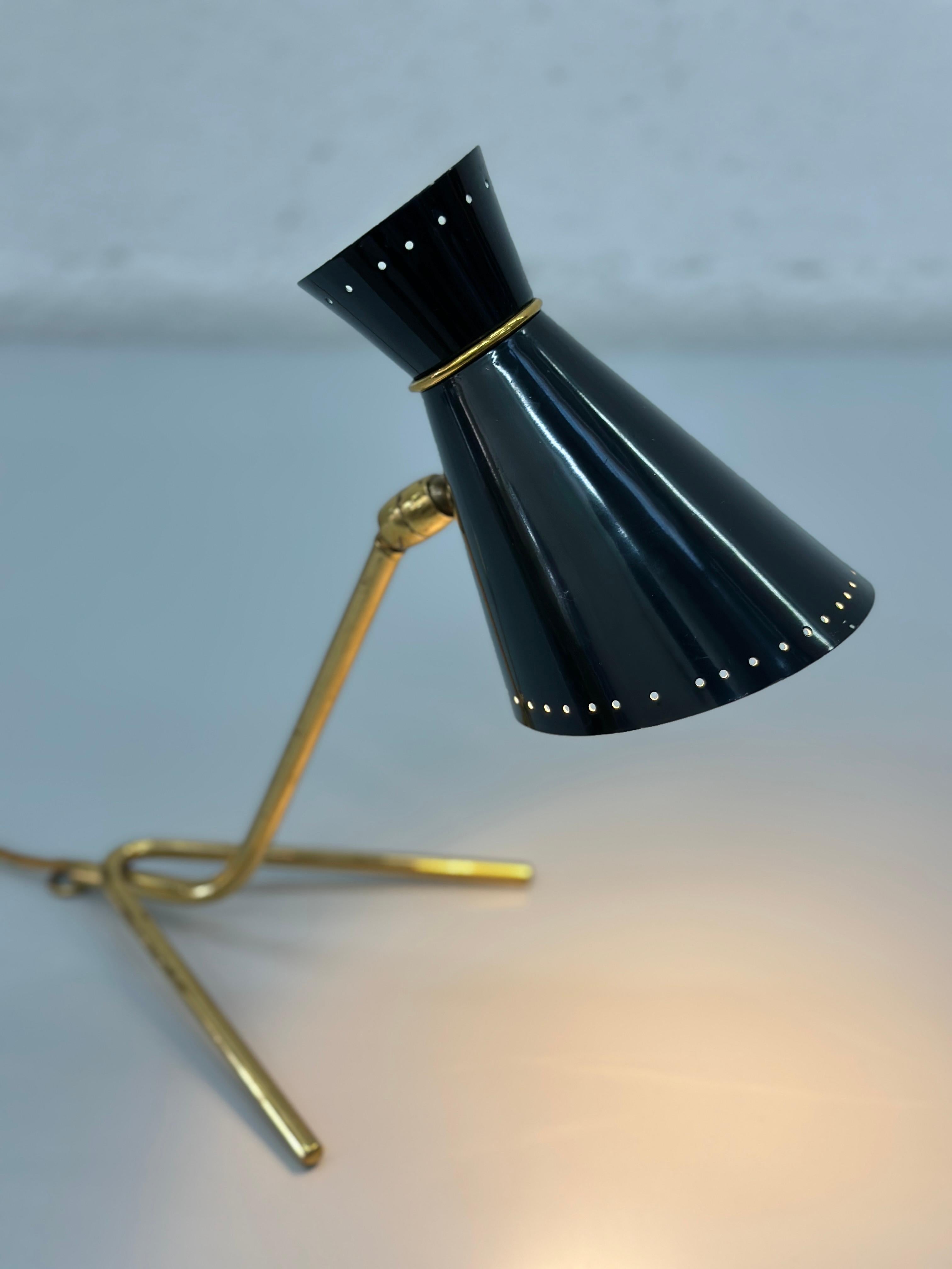 Splendida lampada da tavolo in ottone e nero della metà degli anni '50, che mette in mostra la raffinata eleganza dell'epoca.

La base minimalista in ottone e il paralume conico in metallo laccato verde conferiscono raffinatezza e fascino retrò. Le