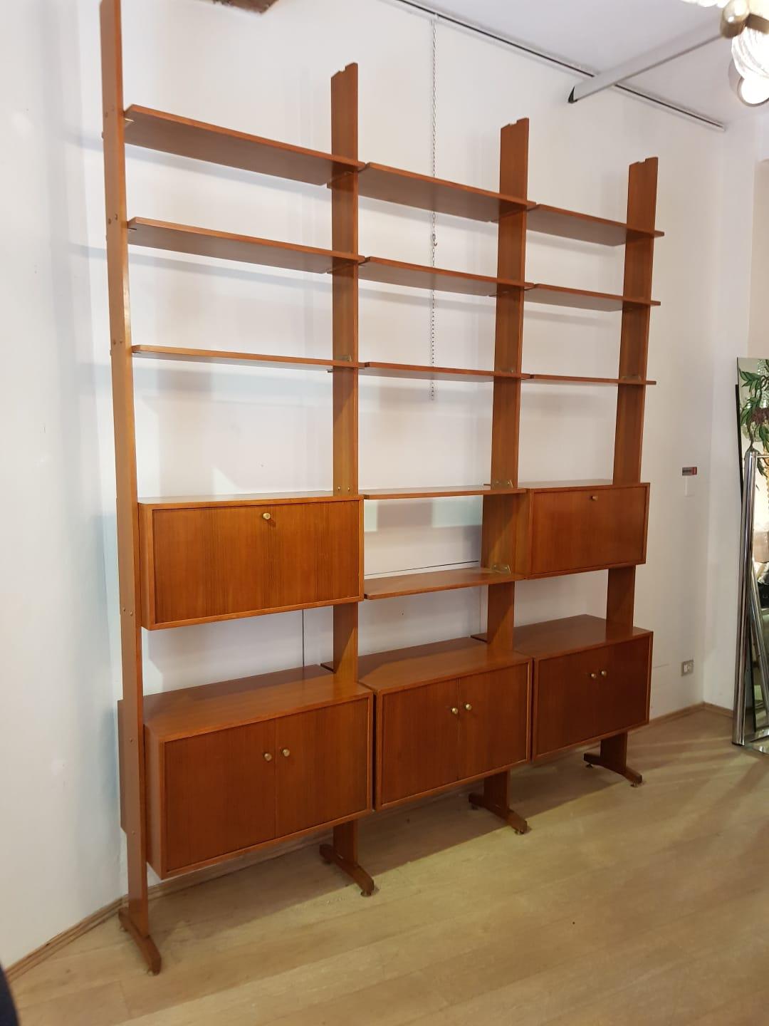 Italian Vintage bookcase from 1950s period. It that can be used to separate a room since it is finished on both sides. it is made of teak wood with brass original hardware. It features three sections, five storage boxes and eleven shelves that can