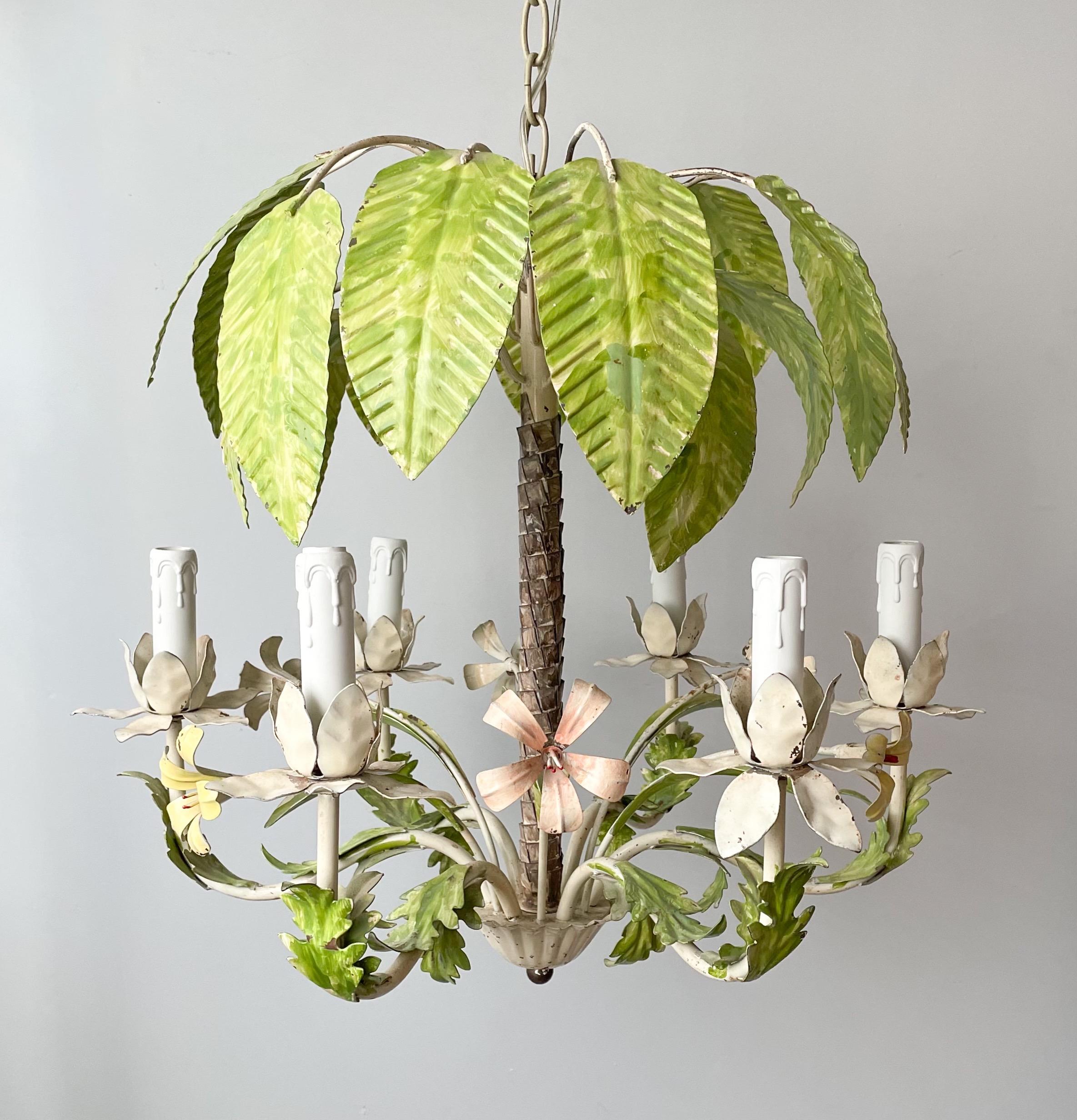 Tropical and fabulous, Italian 1960s painted iron chandelier depicting a palm tree surrounded by lilies of pink and light yellow shades.

The chandelier is constructed of iron with tole-painted finish which shows some wear including minor paint